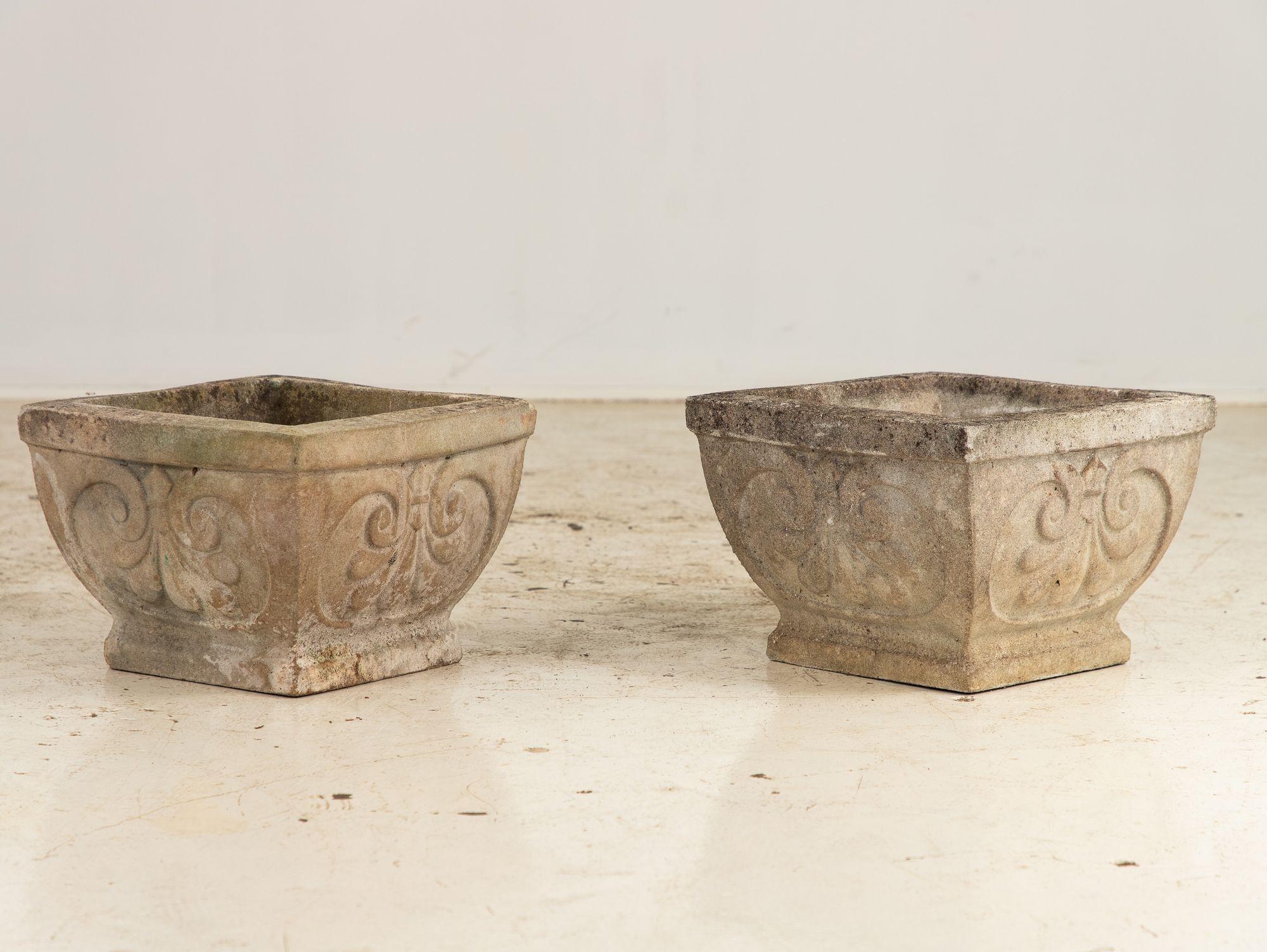 This pair of square concrete stone planters, each tapering gracefully to a narrower base, offers a timeless elegance for garden or patio. Each side showcases a prominent shell design, adding a touch of charm to their sturdy, geometric form. With