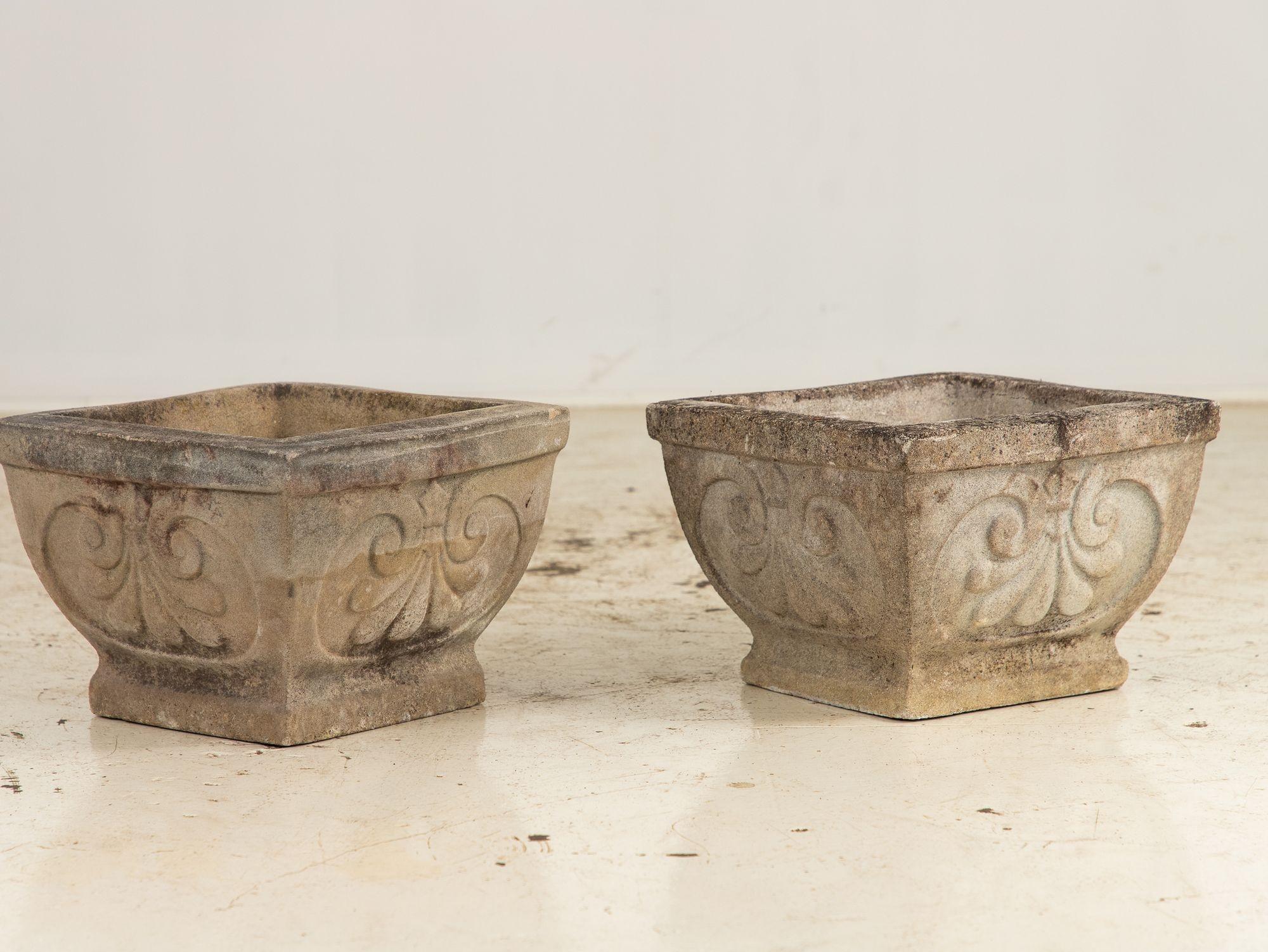 This pair of square concrete stone planters, each tapering gracefully to a narrower base, offers a timeless elegance for garden or patio. Each side showcases a prominent shell design, adding a touch of charm to their sturdy, geometric form. With