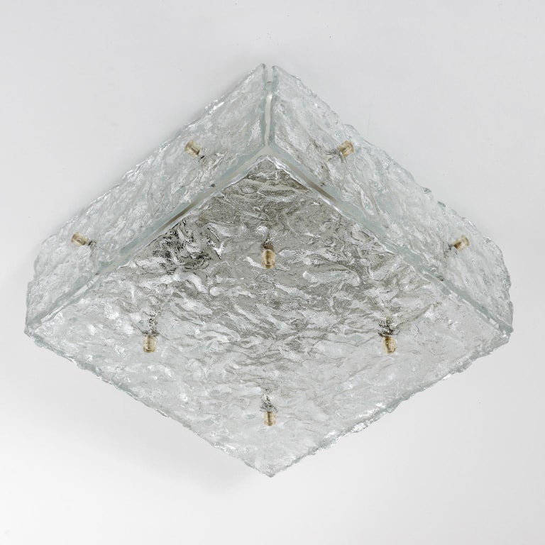 Two squared glass light fixtures by Kalmar, Austria, manufactured in midcentury, circa 1970 (late 1960s or early 1970s).
The lamps are made of square and rectangular textured Murano glass elements which are mounted with Plexiglas bolts onto a white
