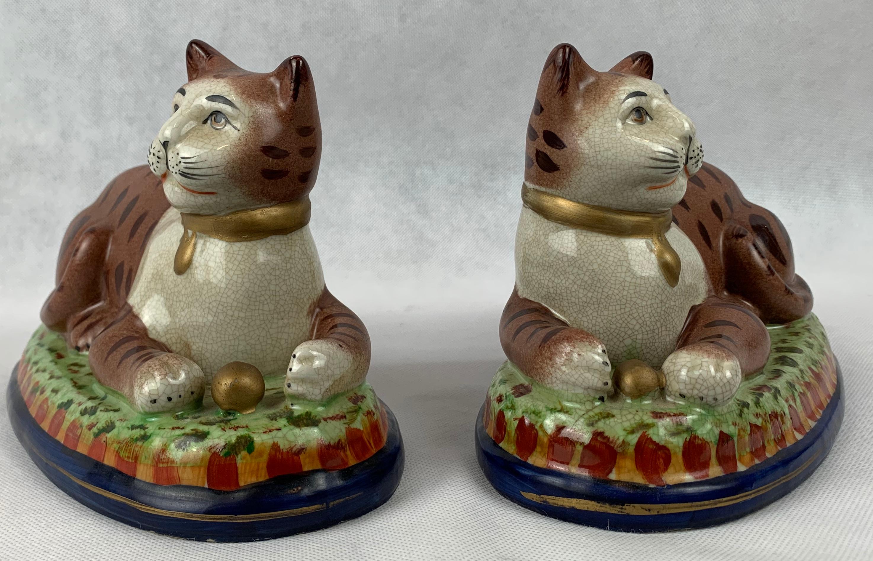 Pair of Victorian style recumbent Staffordshire domestic cats. The hand painting is charming in a naive or primitive style. They are in very fine condition.  Perfect for a mantle or bookcase..... or wherever.