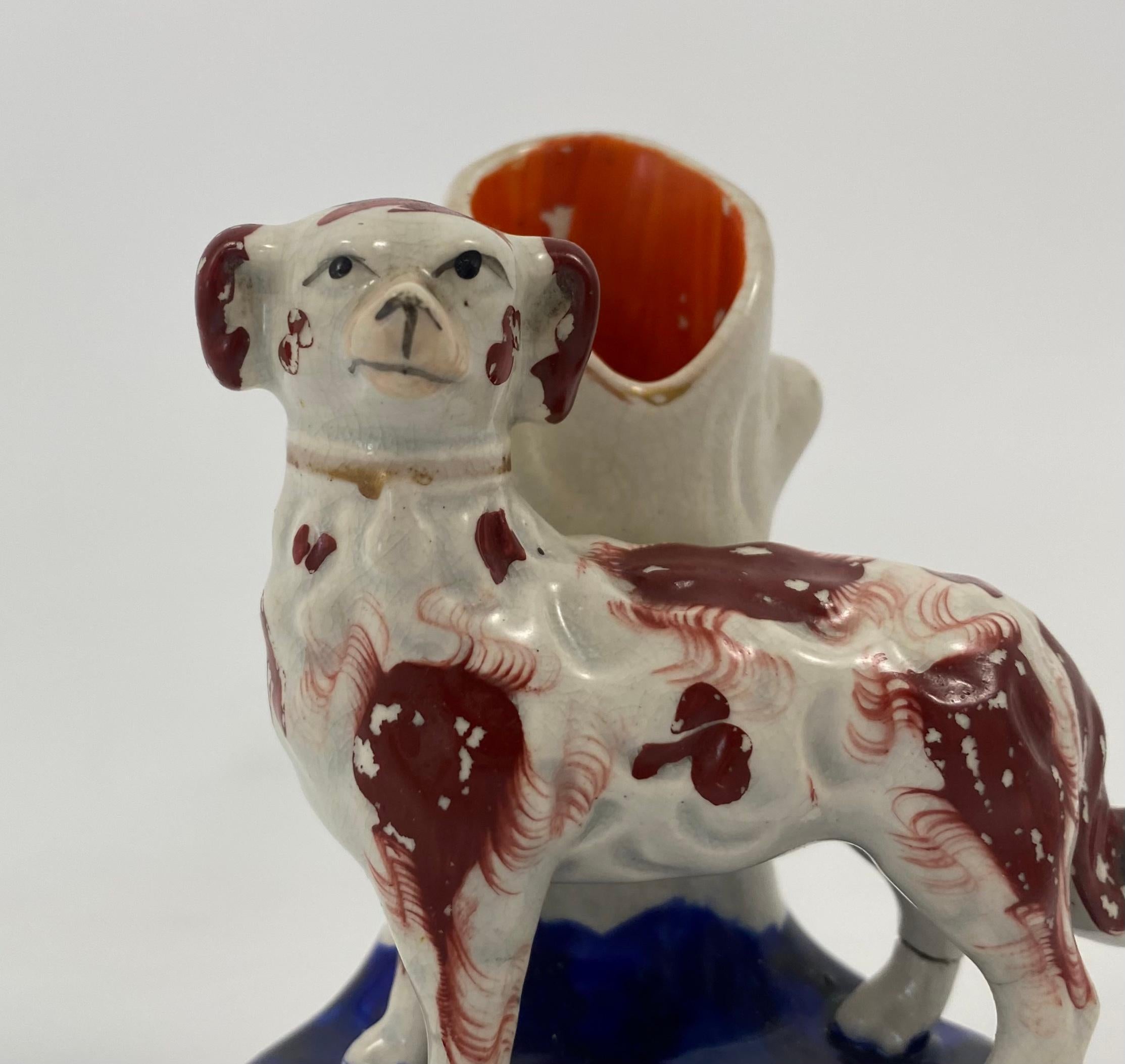 Pair of Staffordshire pottery quill holder spill vases, c. 1860. Well modelled as two dogs, wearing gilt collars, and painted with liver coloured spots, standing before tree trunks, which form the spill vases. Set upon underglaze, cobalt blue mound