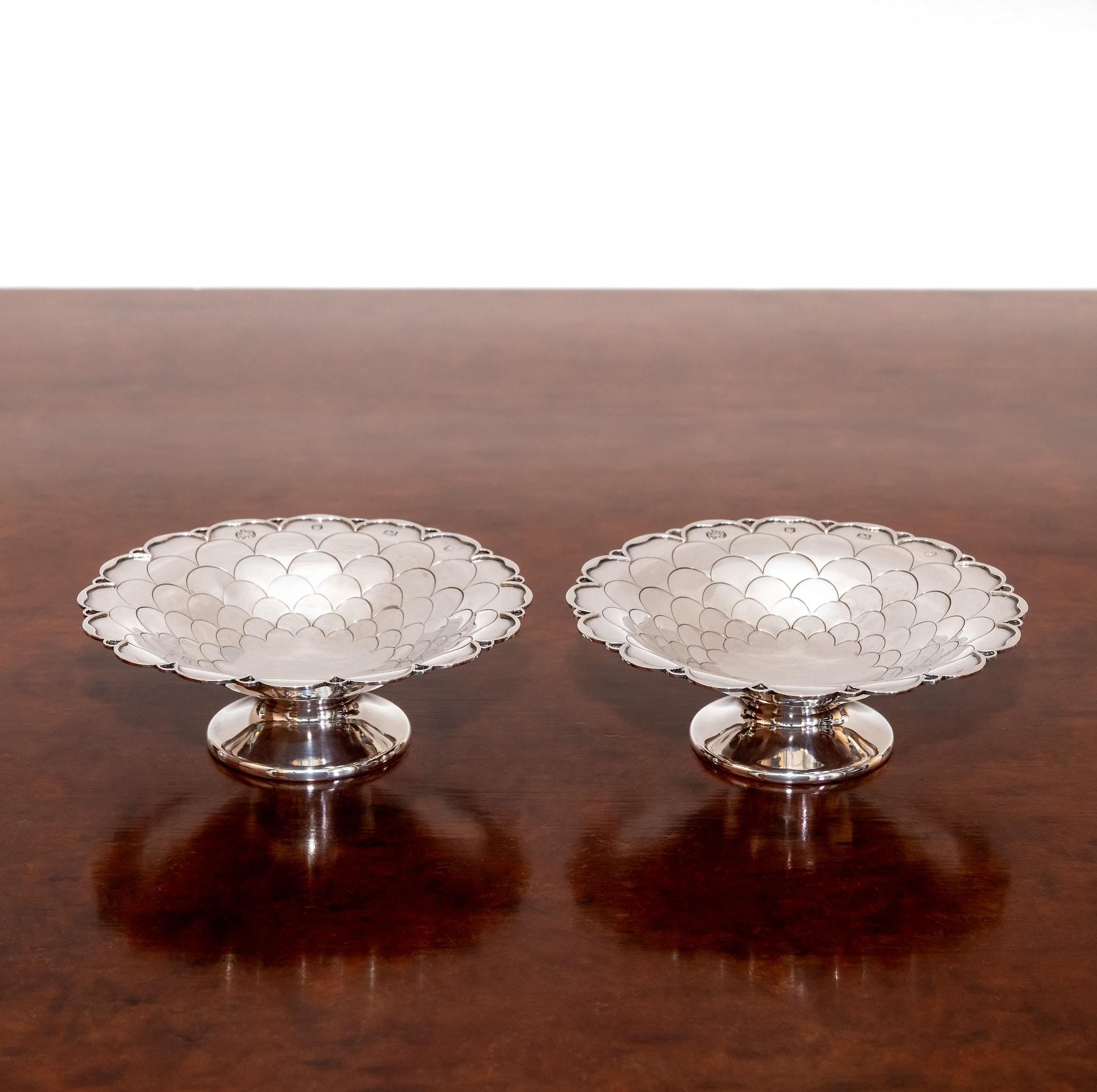 A pair of sterling solid silver bon bon dishes decorated with a fish scale pattern and raised on a circular foot. Hallmarked in Sheffield in 1967 by Elkington and Co.

The pair are in very good condition, showing some light surface marks and some