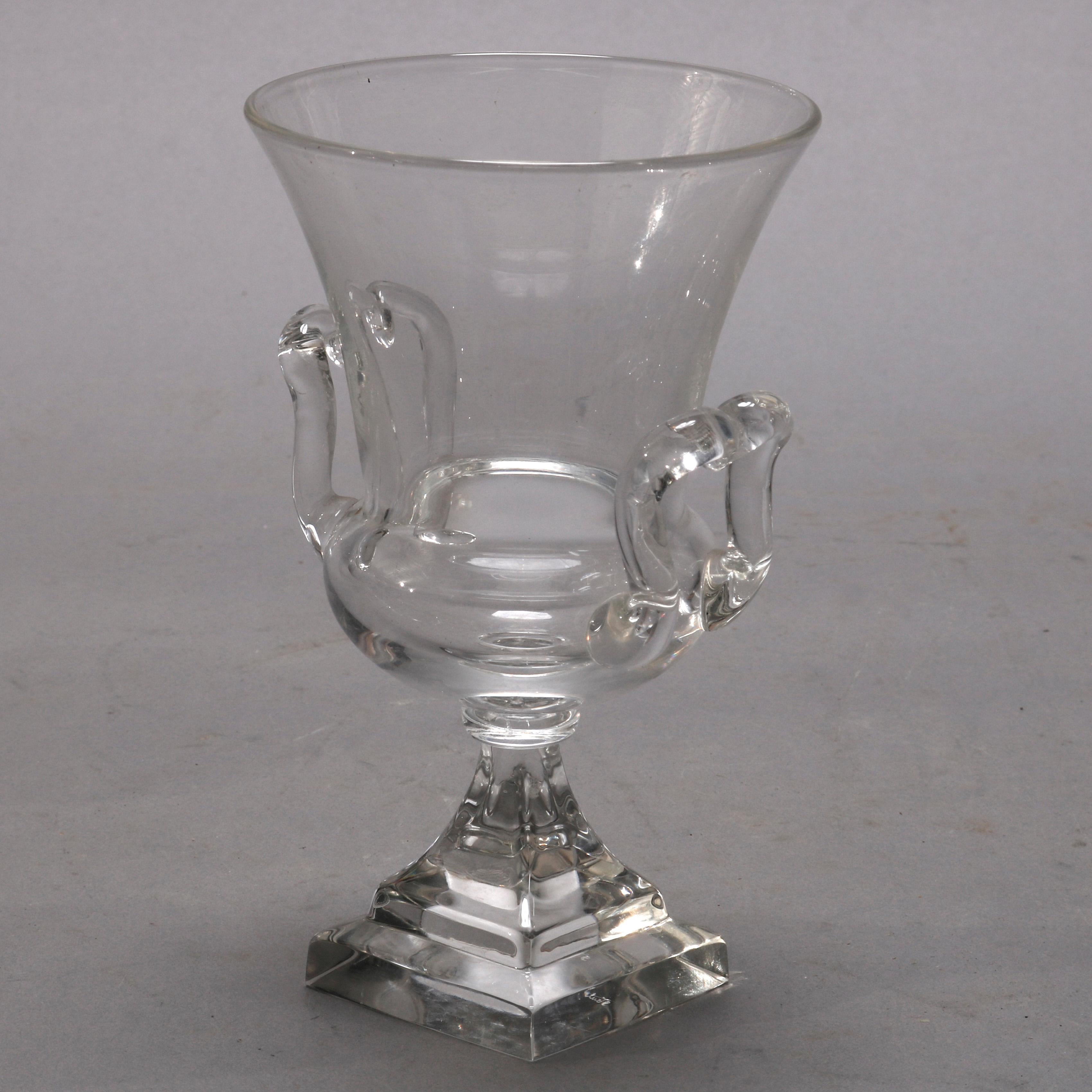 A pair of vintage crystal vessels by Steuben Glass Works offer urn form with applied handles and raised on central plinth, signed on base as photographed, 20th century

Measures - 6.75