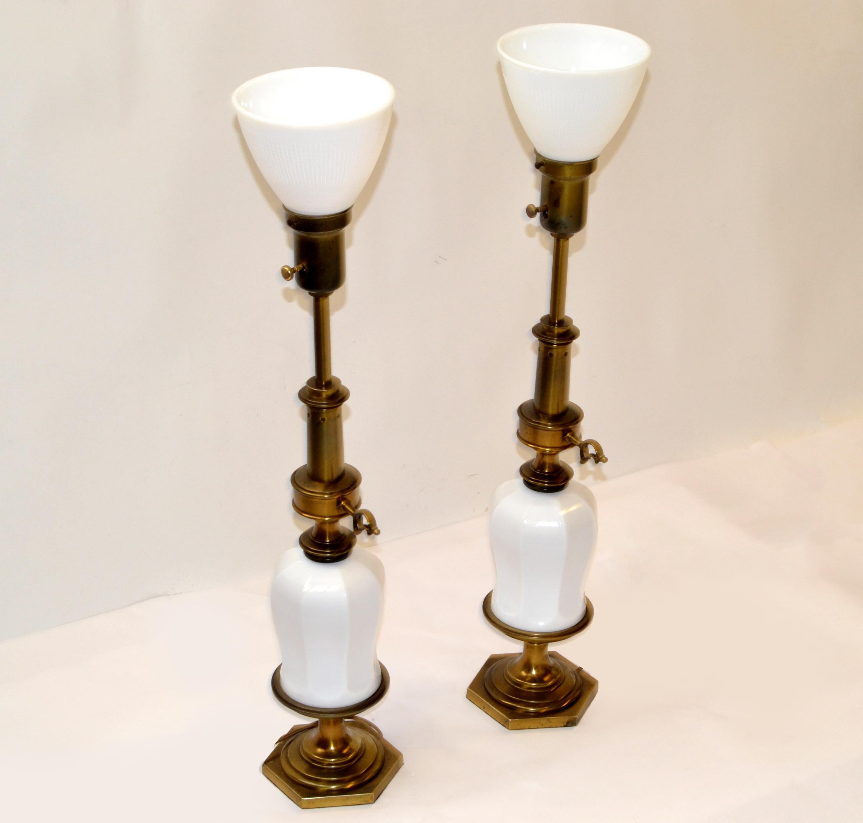 Pair of gorgeous chinoiserie table lamps attributed to Stiffel porcelain vase form body and featuring a classic brass torchiere and pedestal. Original long brass torchiere style stem with a milk glass diffuser. 
The shaped porcelain bodies are free