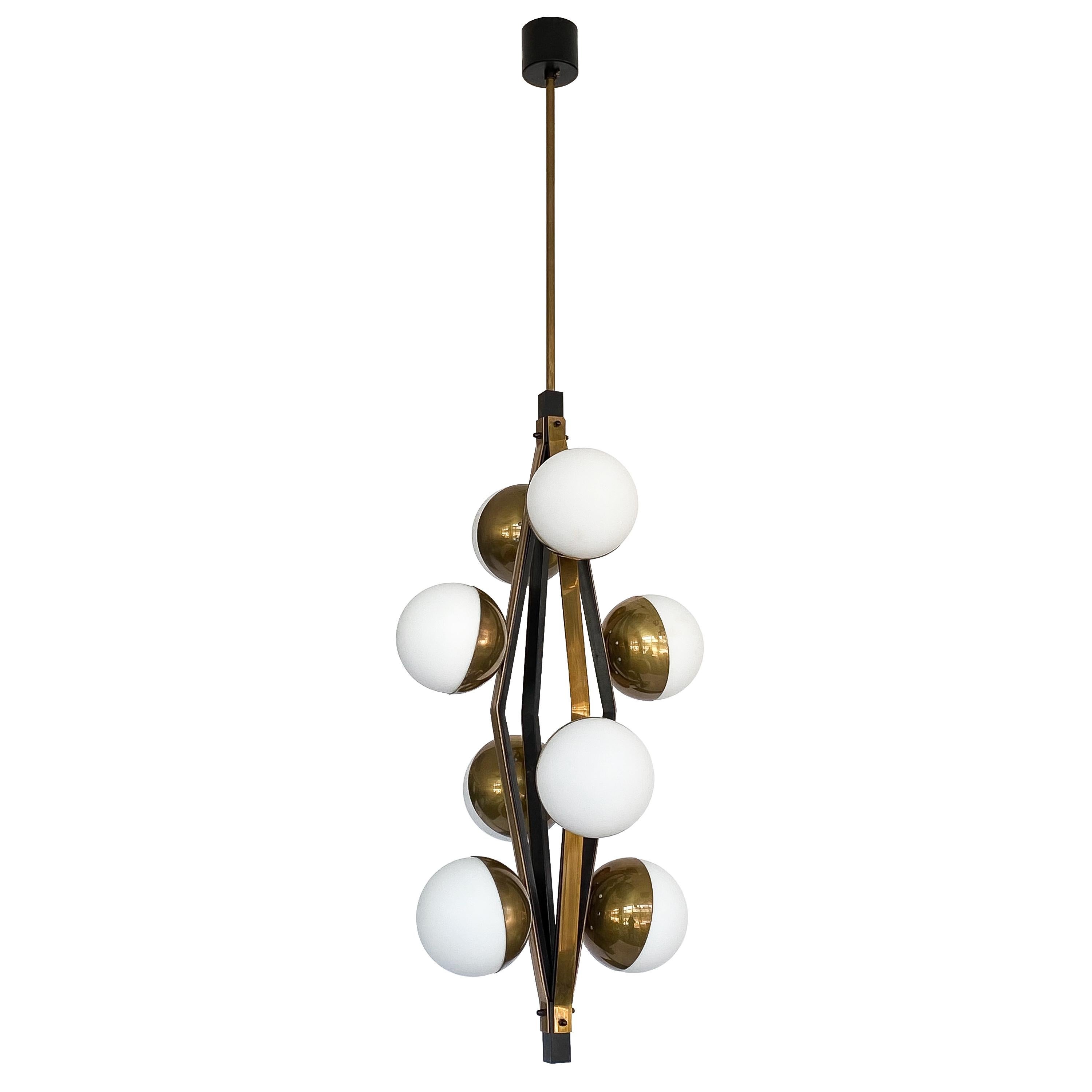 Stilnovo patinated brass pendant chandeliers with eight satin oplaine glass globes, Italy, circa 1950s. Priced individually. These Italian chandeliers feature a geometric diamond shaped open framework in blackened iron and beautifully patinated
