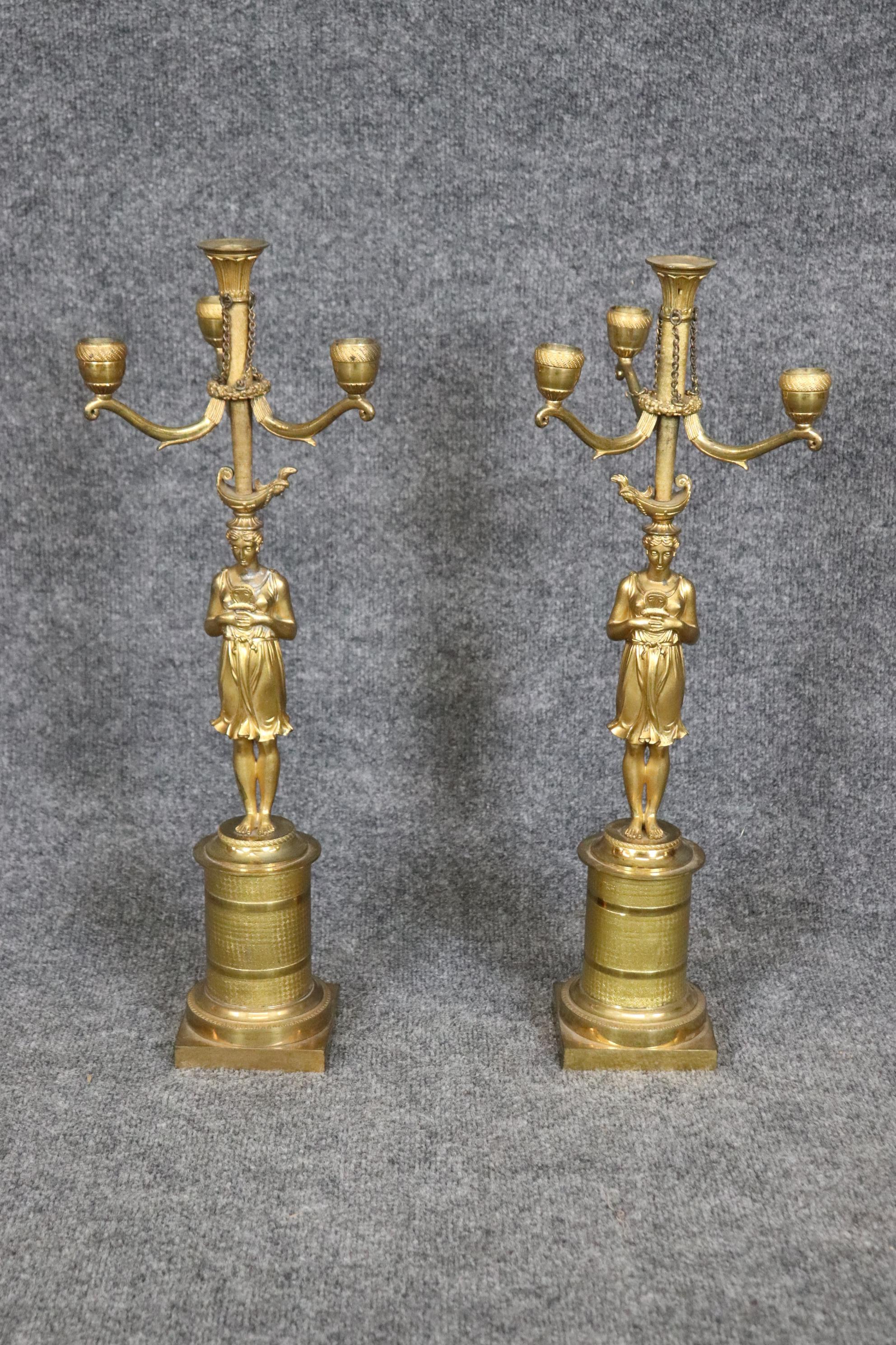 This is a stunning pair of bright bronze with expertly cast life-like figural ladies holding the candle holder tops. These could be wired for lighting and shades added.  Measures 22 tall x 7.25 wide x 8 inches deep. Dates to the 1880s era. 