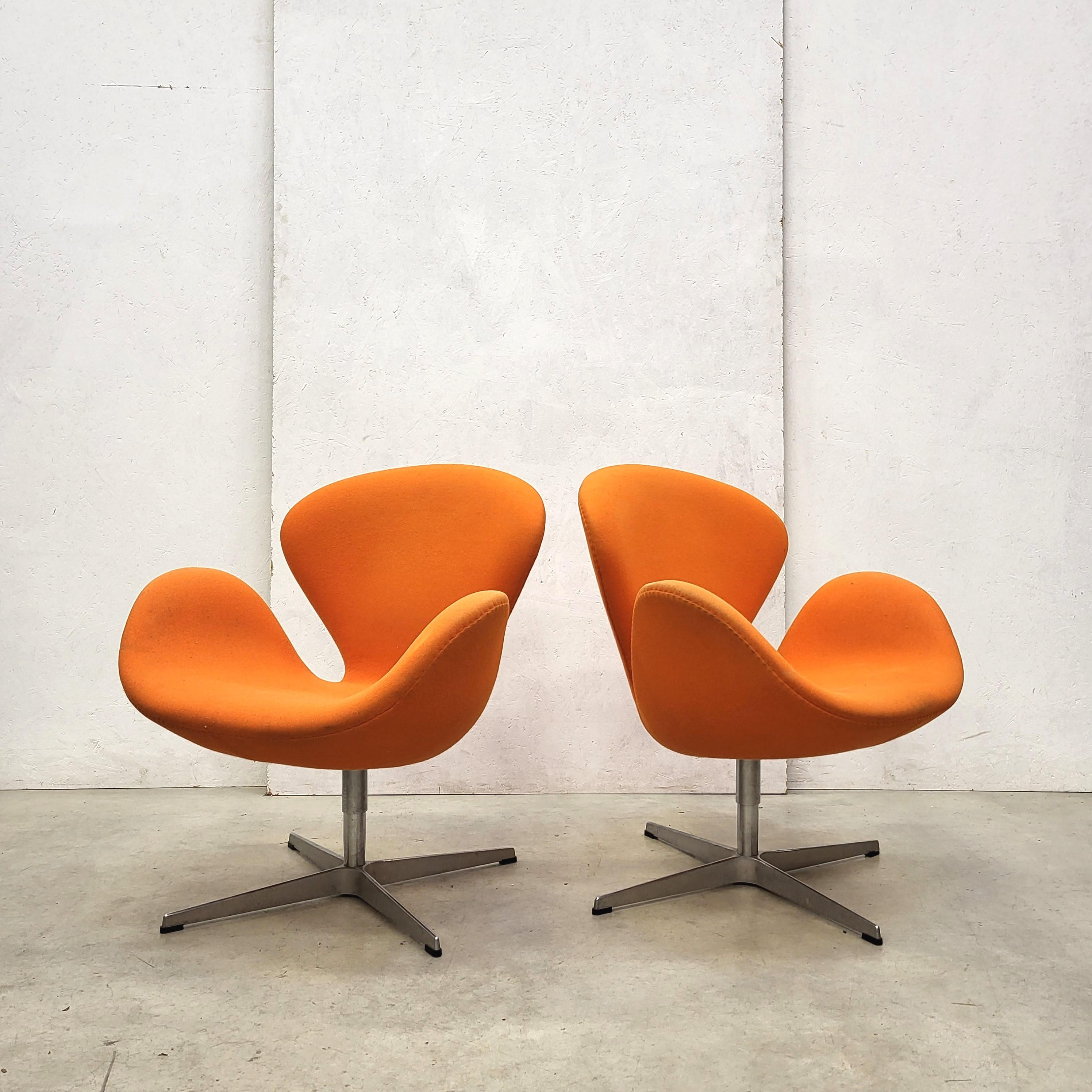 These Swan chairs were designed in the 1950s by Arne Jacobsen for the SAS Hotel in Copenhagen and produced by Fritz Hansen in 2006. 

The chair features a wonderful orange fabric upholstery. 
The pieces coming with the original Fritz Hansen label