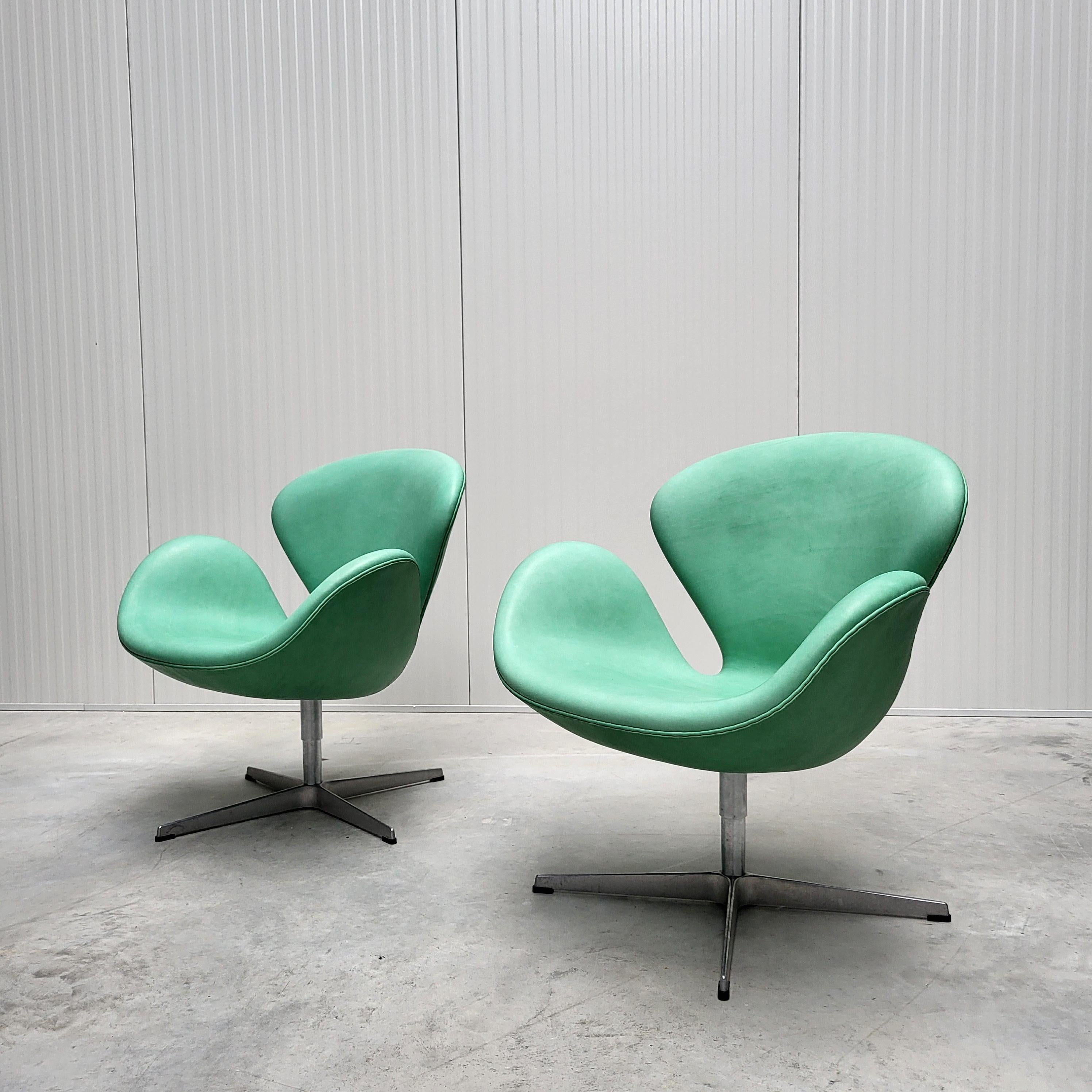 This wonderful set of 2x Swan chairs were designed in the 1950s by Arne Jacobsen for the SAS Hotel in Copenhagen and produced by Fritz Hansen in 2006. 

The Swan set features an amazing and custom made Mint Green Naturale leather upholstery. 
The