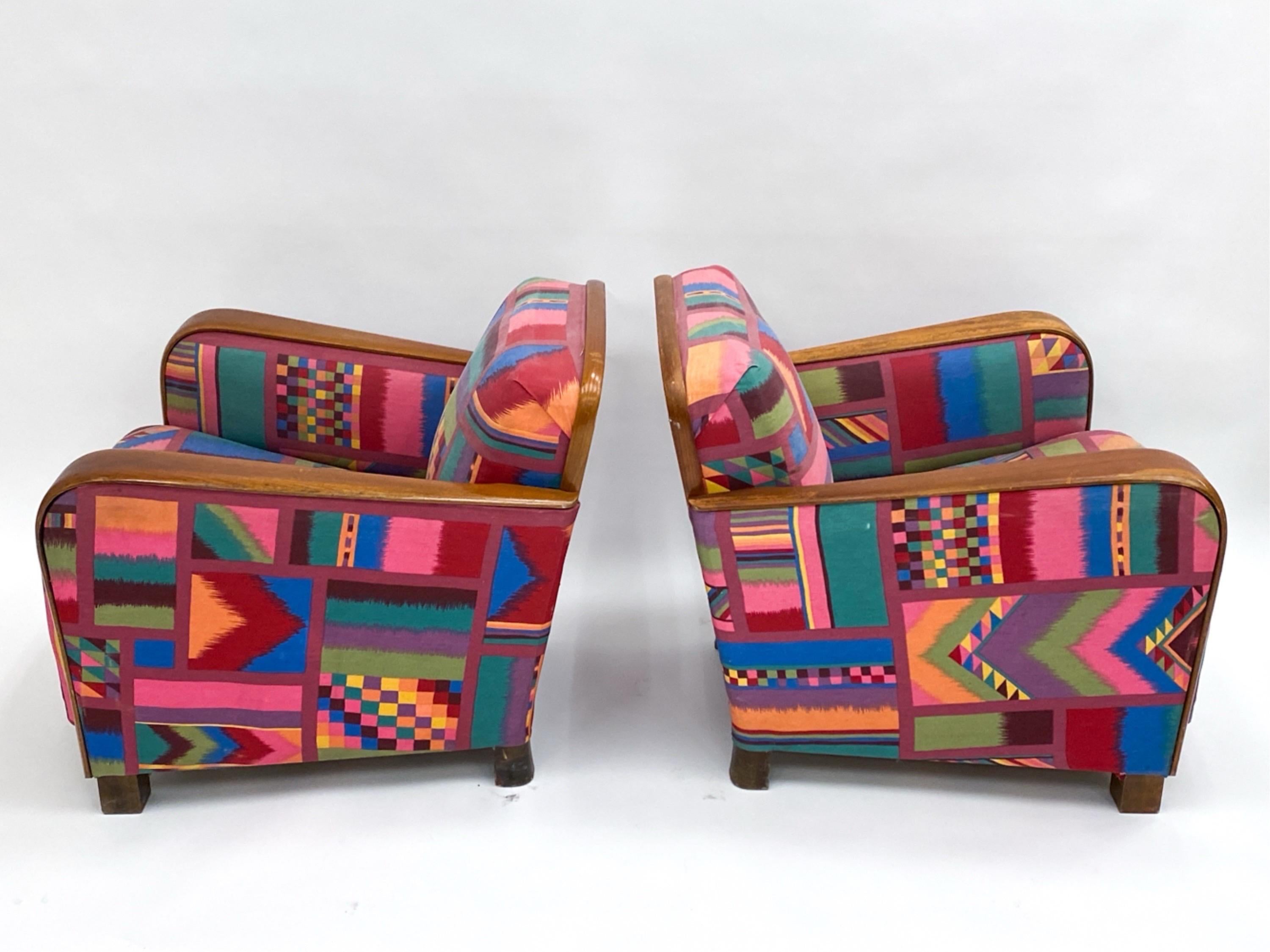 Iconic pair of Art Deco period armchairs. Teak armrests compliment multi patterned modern style fabric upholstery. 