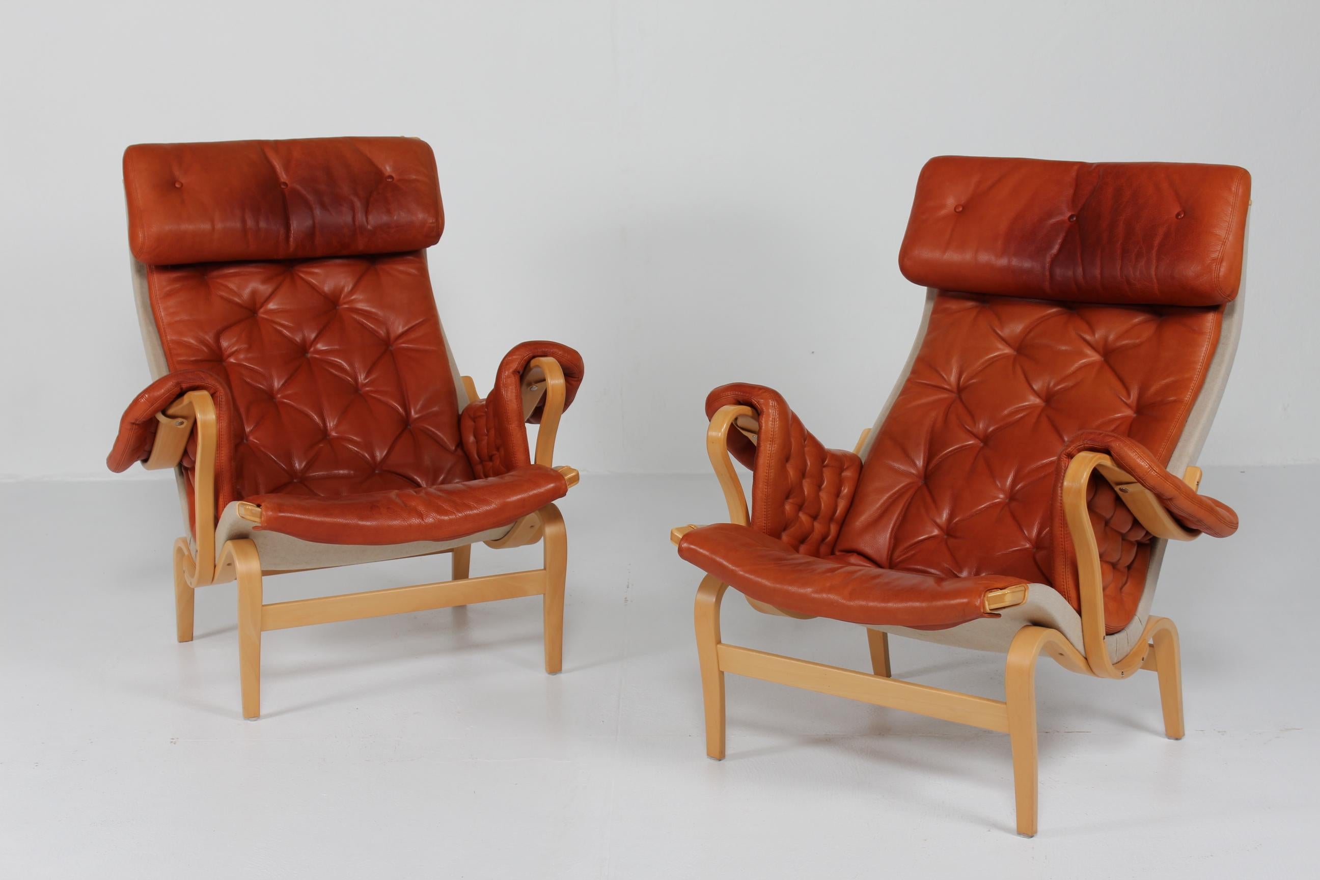 Conjunto de dos butacas Pernilla del diseñador de muebles sueco Bruno Mathsson fabricadas por Dux

Las sillas son de haya curvada al vapor lacada y tensada con lona. Tapicería de cuero natural de color marrón rojizo/cognac con buena pátina.

Las
