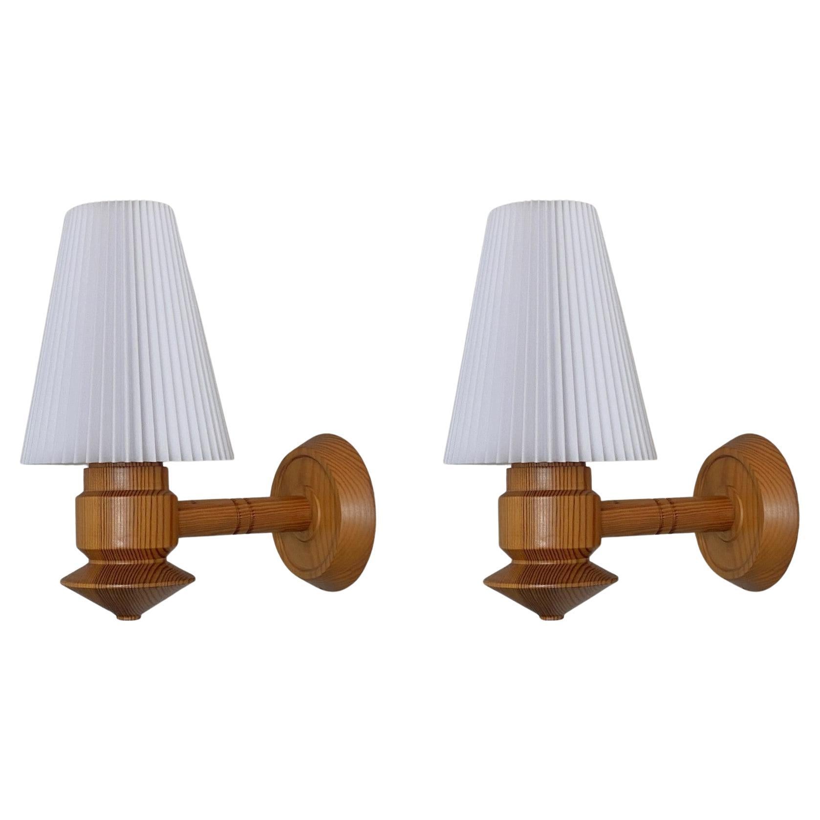 A lovely pair of solid hand-carved pine wood wall sconces designed and produced in Sweden in the 1970s. Clean lines and organic design from the Scandinavian Modern period, beautifuly hand-carved with pleated plastic lampshades. Both sconces in very