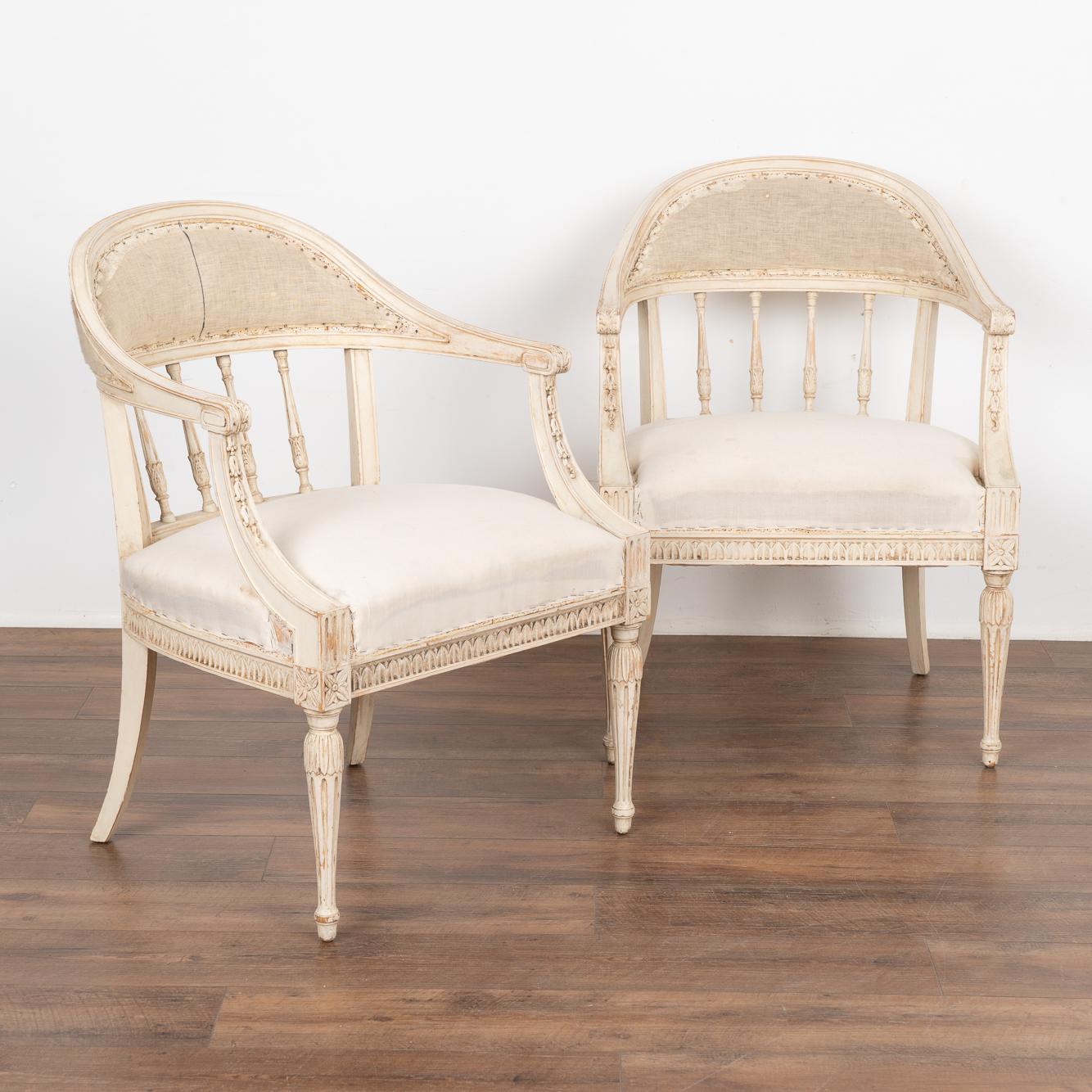 Pair, Swedish Gustavian arm chairs with a gently curved barrel back, decorative turned spindles and sabre back legs, adding to the graceful appeal of each.
Fluted turned front legs and decorative carving embellish the skirt, arms and legs. 
The