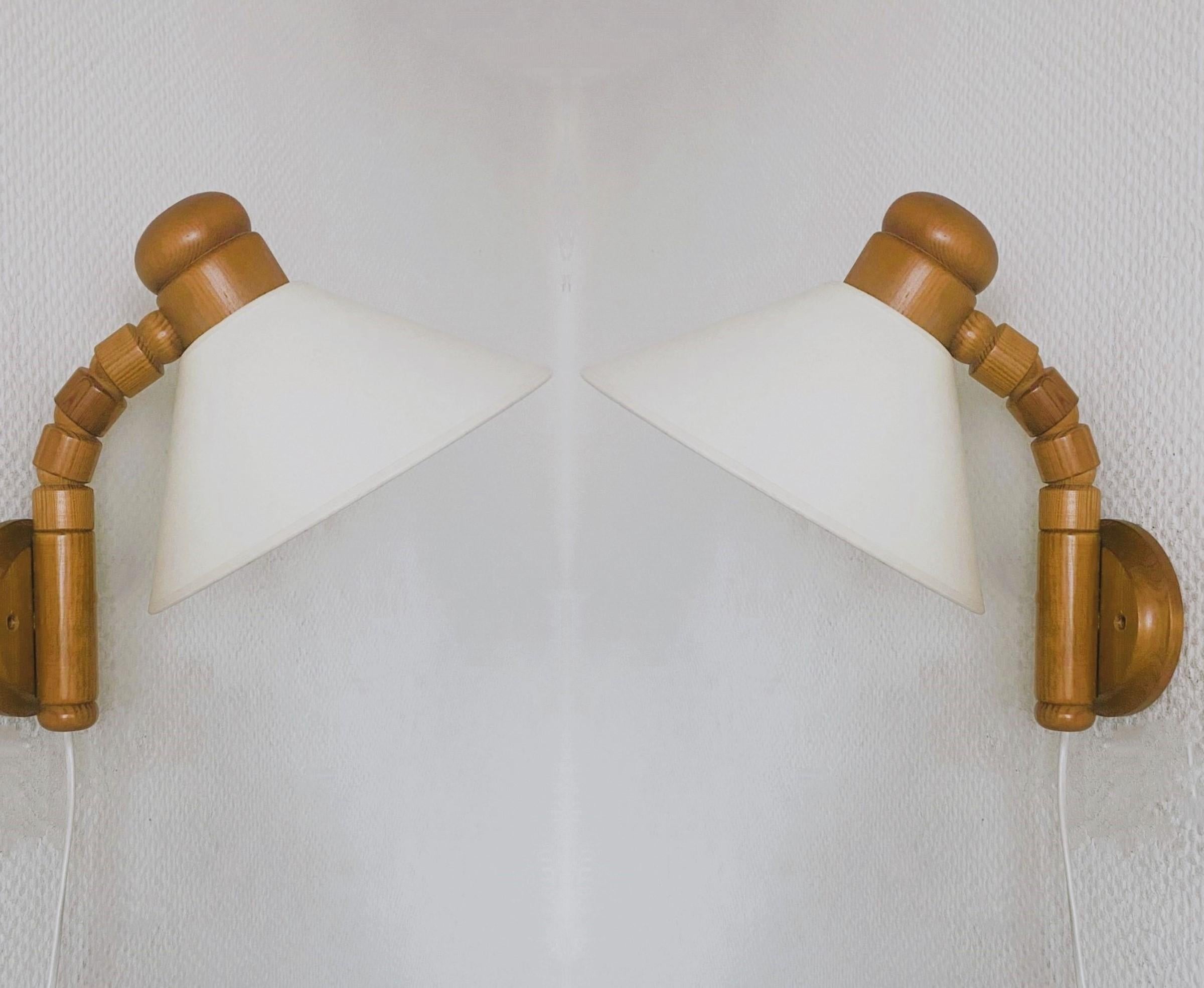Ein Paar Wandleuchten aus Kiefernholz, entworfen von Solbackens Svarveri, hergestellt in Schweden in den 1960er Jahren. Klare Linien und organisches Design aus der Zeit der skandinavischen Moderne, mit cremefarbenen Stofflampenschirmen. Der