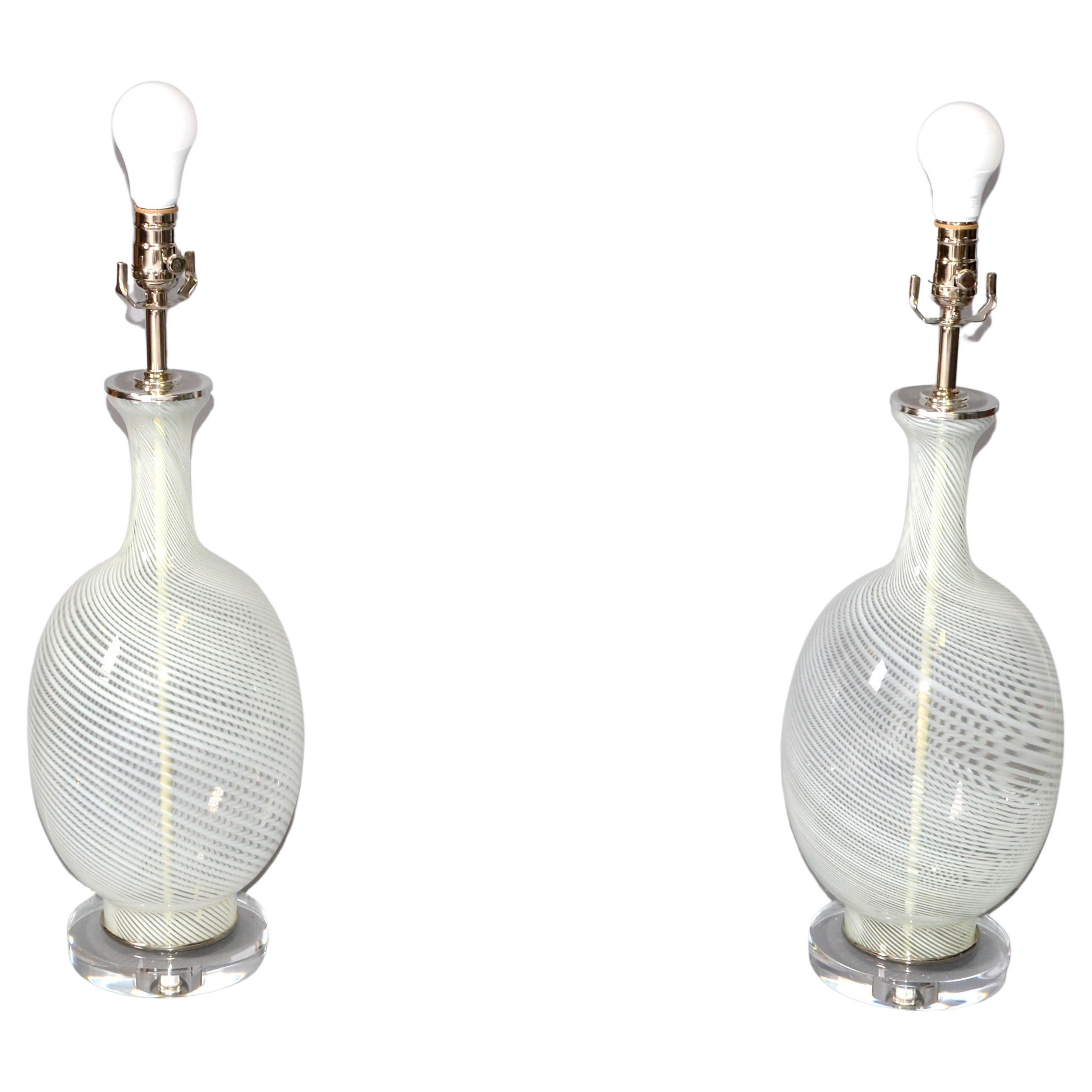Ein Paar mundgeblasene Kunstglas-Tischlampen von Blenko aus der Jahrhundertmitte.
Der gewirbelte, transparente Glaskörper ist auf einem Acrylsockel montiert und hat einen vernickelten Deckel mit Hals.
In perfektem Zustand und verwendet eine