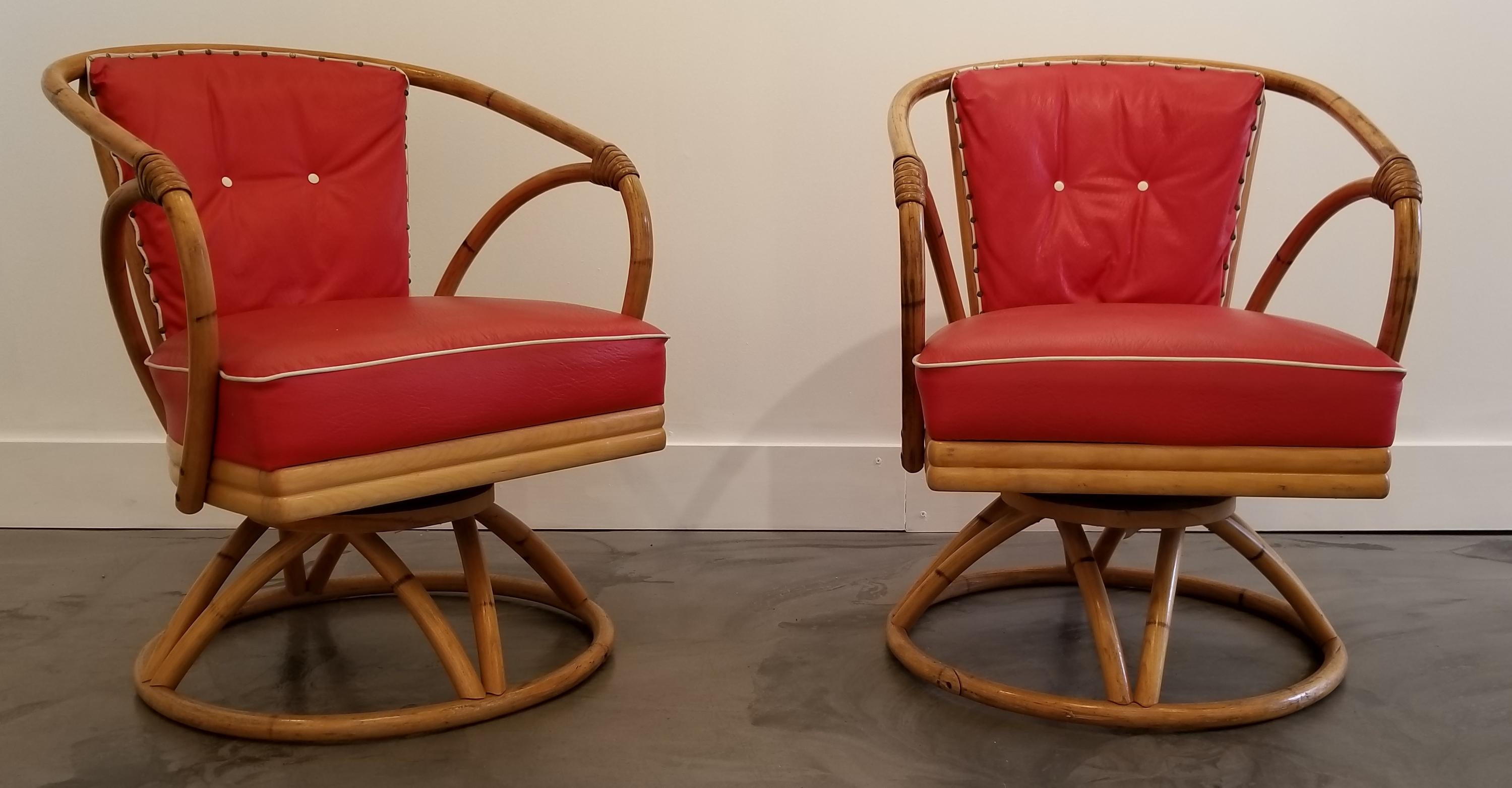 A pair of swivel lounge chairs made of steamed oak and rattan. Very good vintage condition with original red vinyl upholstery. Structurally very solid, swivel has spring return to original position. Retain Heywood-Wakefield labels, circa 1950s.