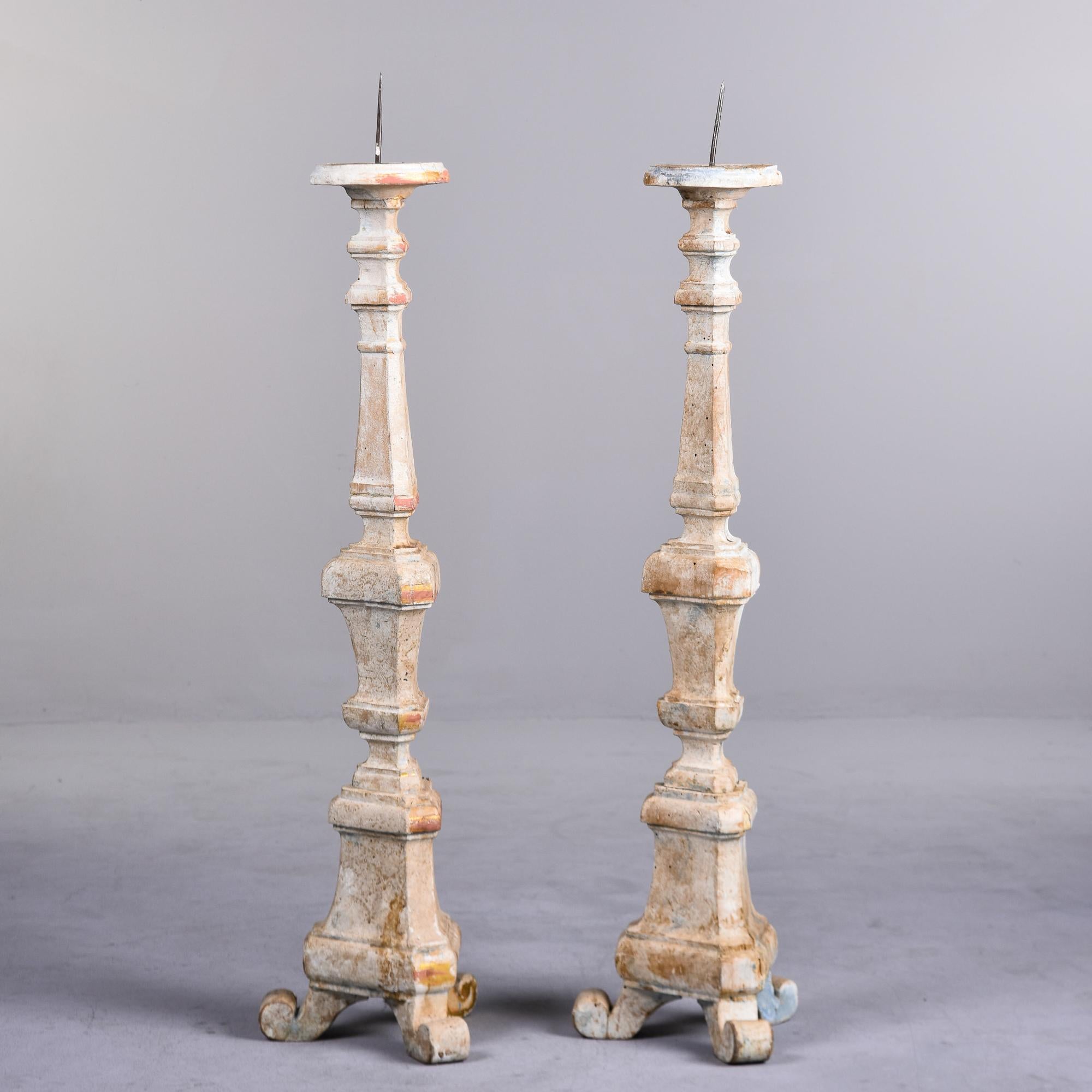 Found in Italy, this pair of carved and painted pine pricket sticks date from about 1870s. Curved, three footed base with antique white painted finish with some gilded paint showing through. Unknown maker. Priced and sold as a pair.