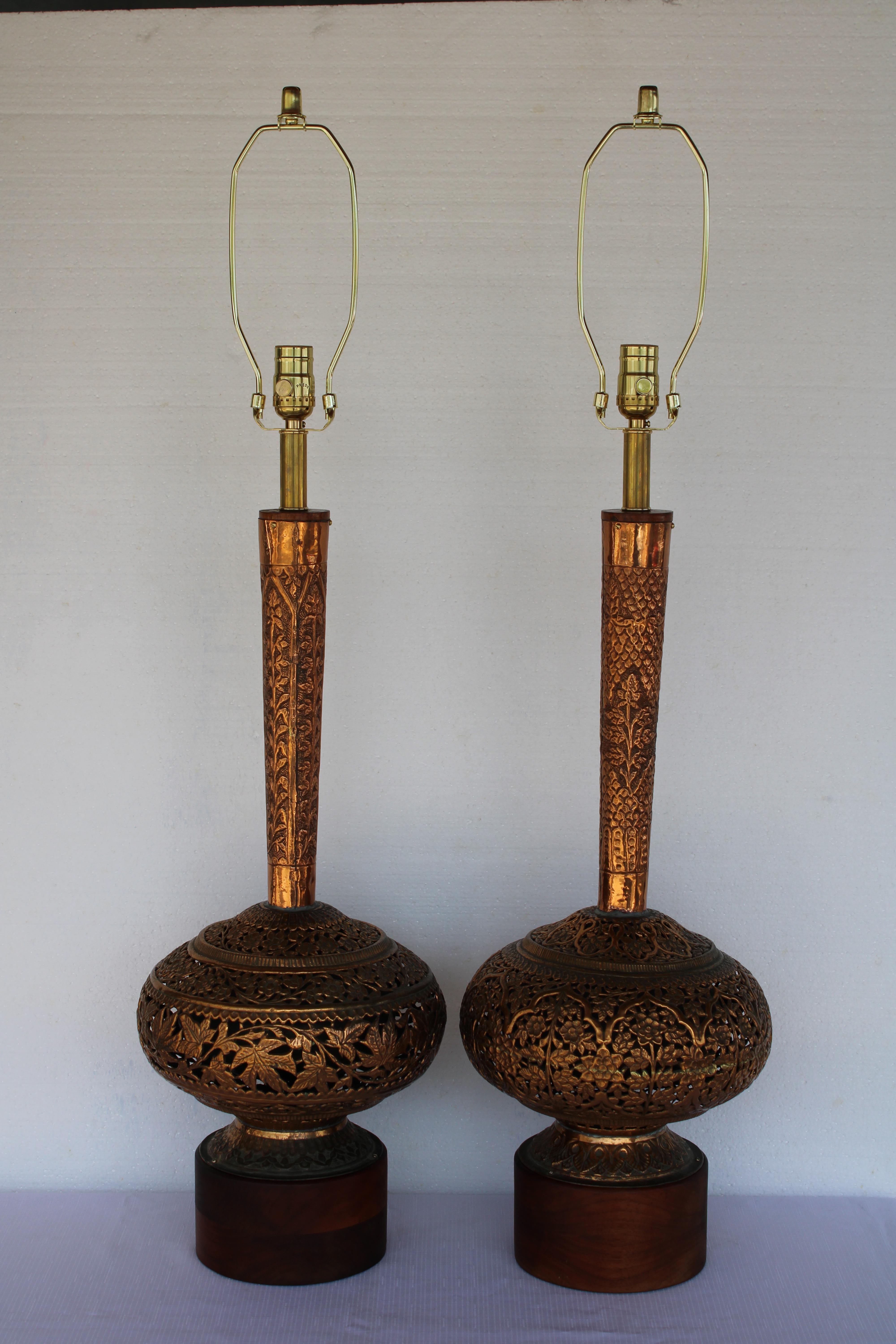 Lámparas de sobremesa altas de cobre repoussé con bases de madera maciza de teca. Los intrincados calados de las partes inferiores crean interesantes juegos de luces. Proceden de la herencia del propietario original, que las trajo de Marruecos en