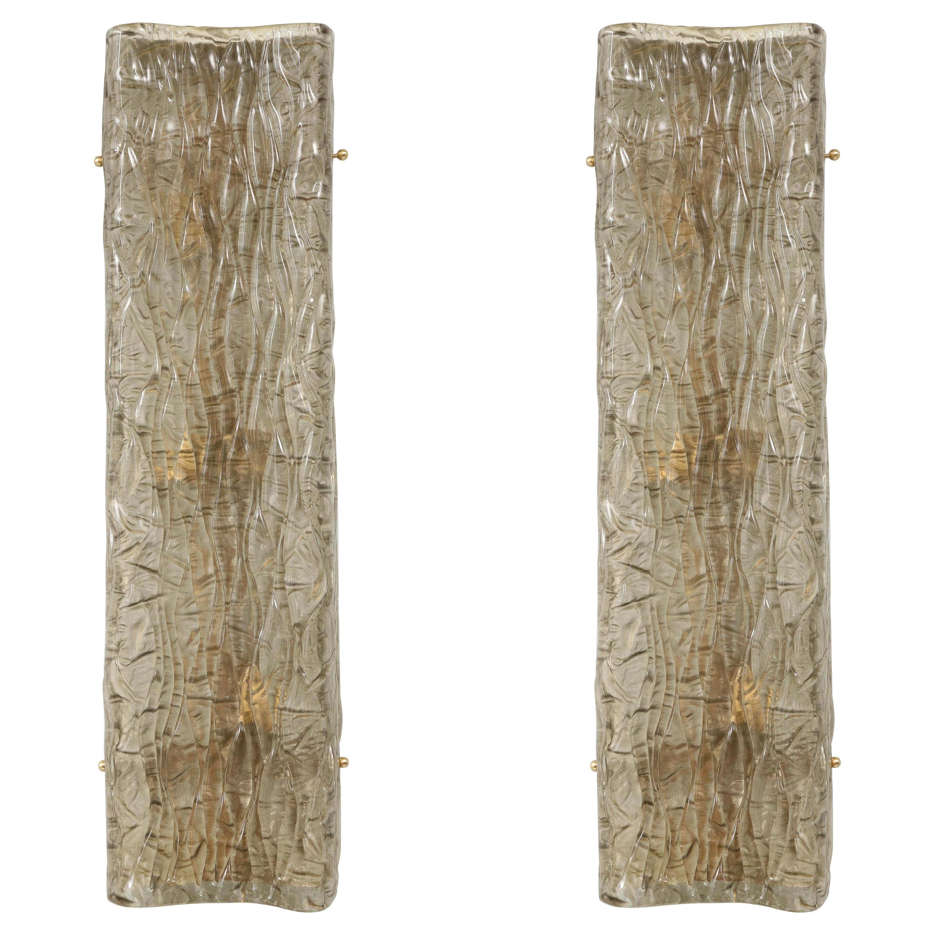 Tall wall sconces in a slightly smoked glass with veins. Each sconce has four lights. American wired. 