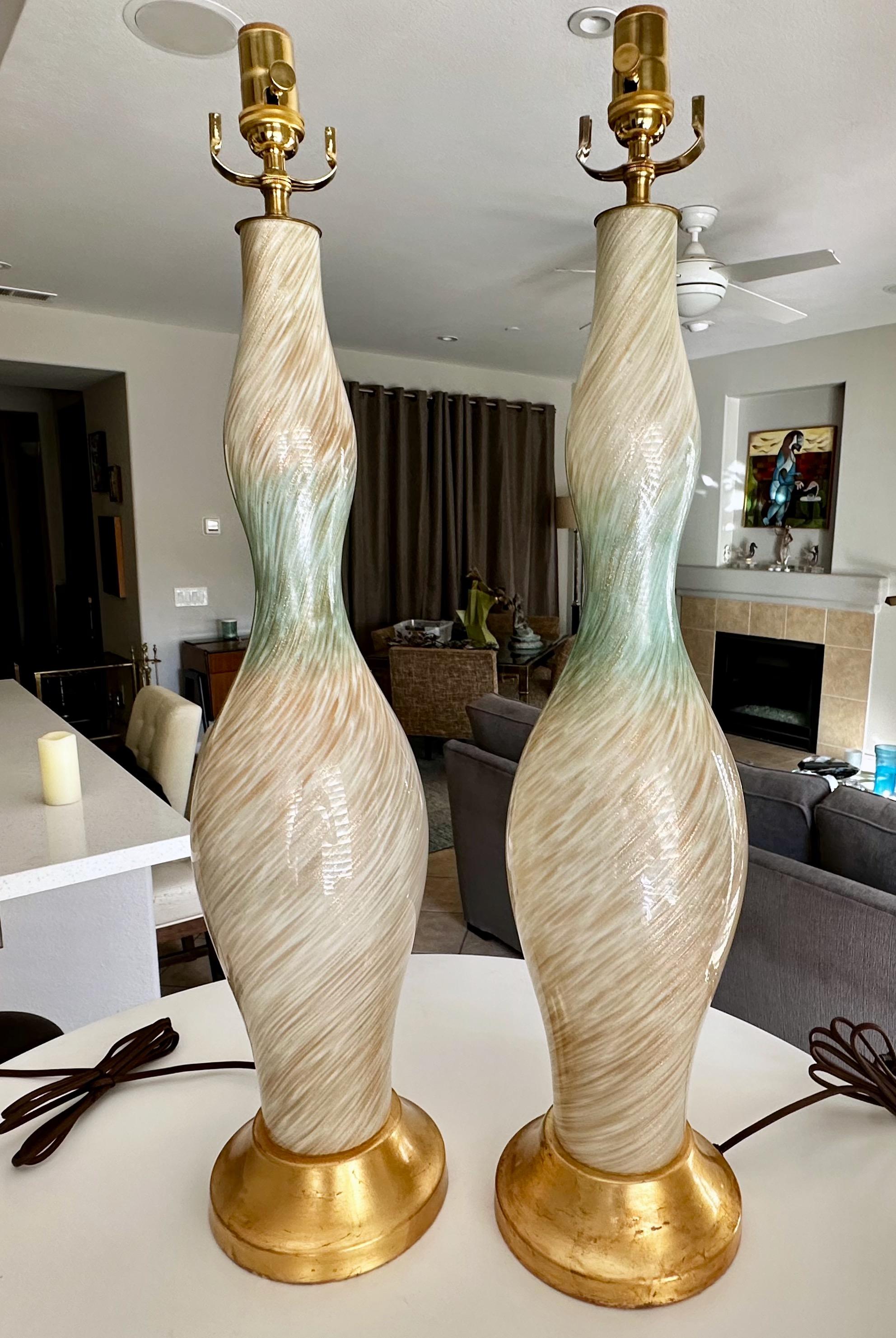Pair of tall Murano Italian mid century hand blown cased white and splash of light blue table lamps. The glass bodies are covered with swirls of striped copper adventurine, resting on gilt metal bases. Newly wired with new brass 3 way dimmer sockets