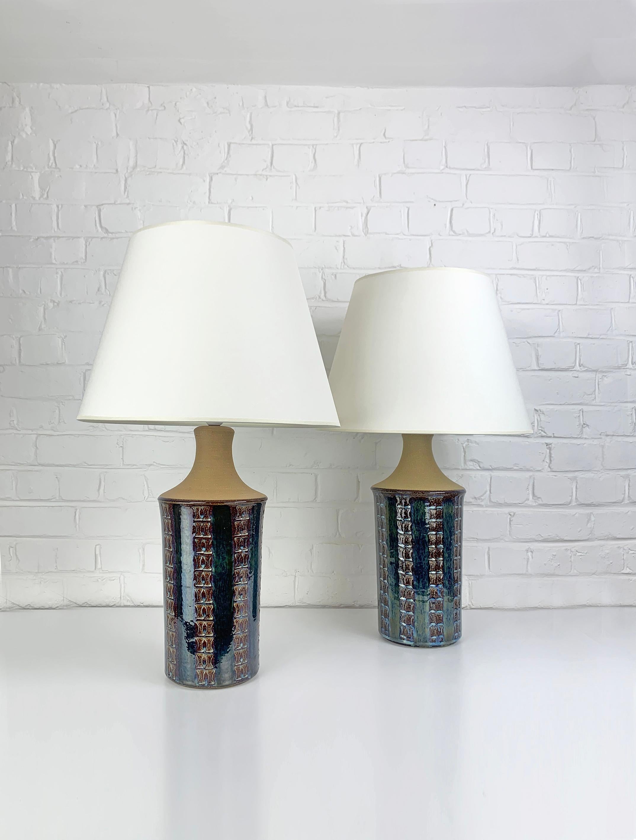 Coppia di grandi lampade da tavolo danesi del Mid-Century in gres degli anni 1960-70.   

La parte inferiore delle lampade è smaltata in blu scuro con accenti verde scuro-marrone-giallastro e blu chiaro e decorata con un motivo impresso. La parte
