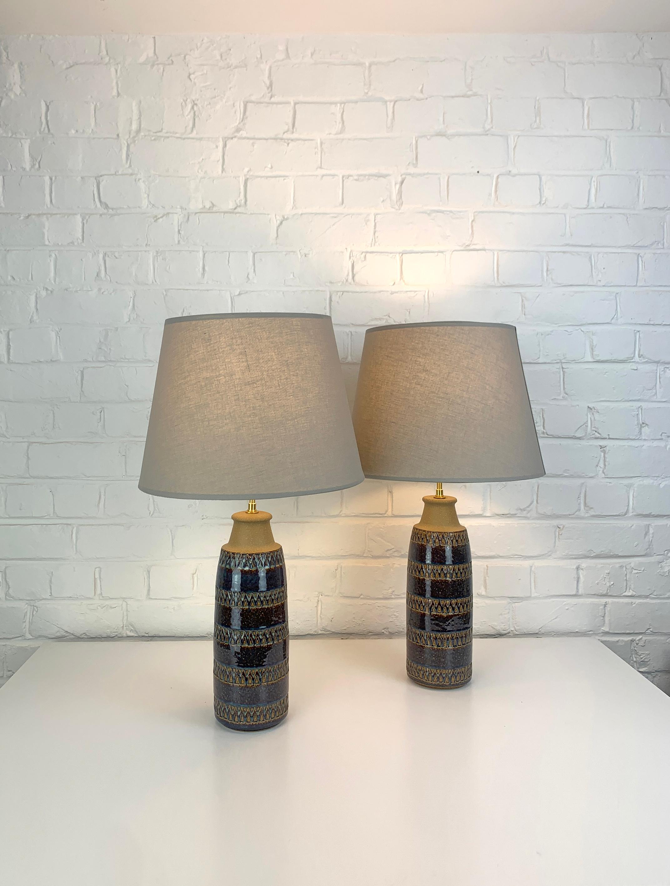 Pair of tall Danish Mid-Century stoneware table lamps of the 1960-70s.   

The bottom part of the lamps is glazed in a dark reddish brown with blue  and ochre accents, decorated with an impressed double triangle pattern. The upper part is not glazed