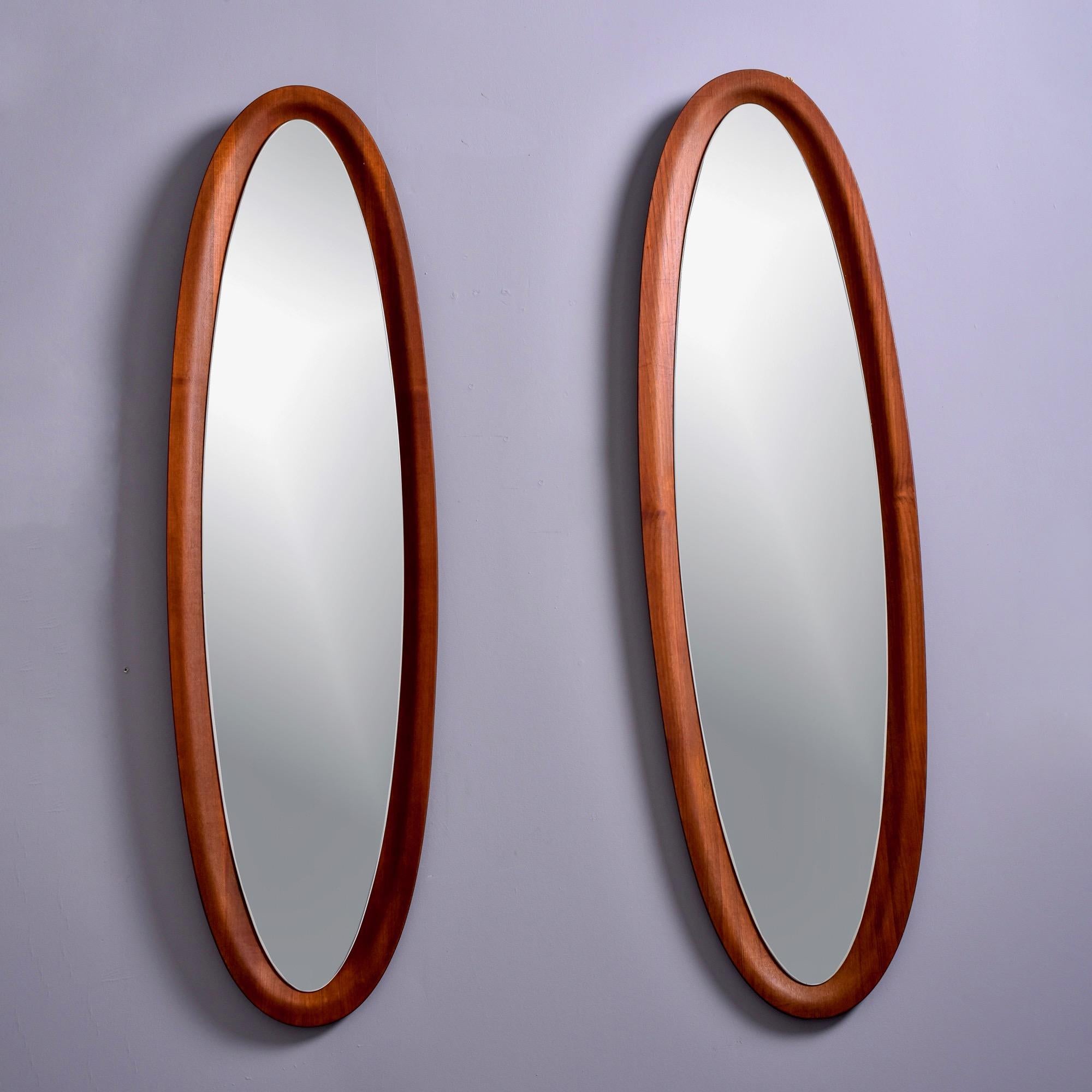 Found in Italy, this pair of circa 1960s oval mirrors have wood frames that appear to be walnut. Frames have a bowl-form shape and mirrors are set into them. Unknown maker. Sold and priced as a pair. 

Actual Mirror Size: 52” h x 12” w.