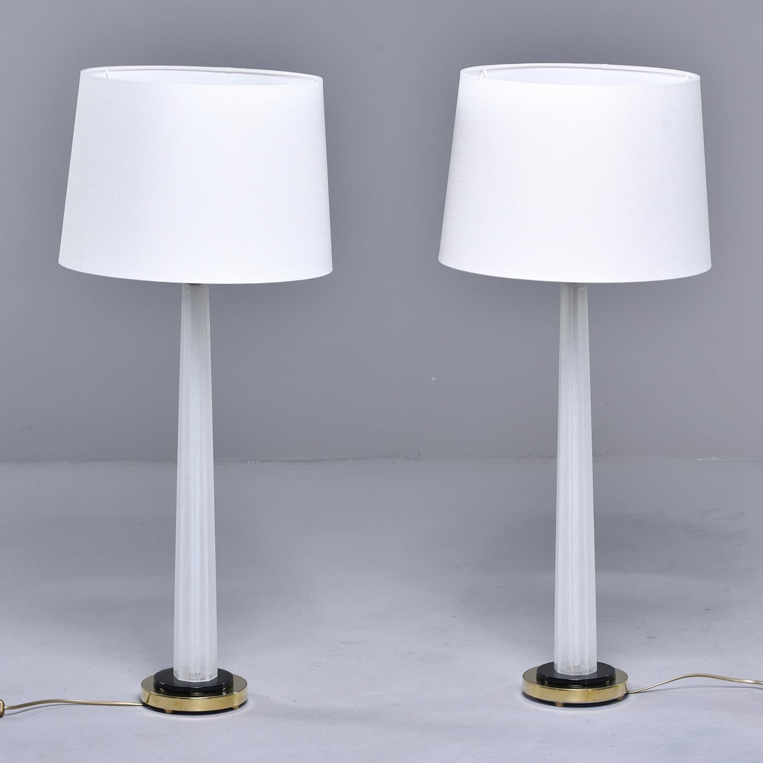 Pair of tall, slightly tapered white Murano glass table lamps attributed to Seguso. Contrasting base of black with brass fittings. Newly wired for US electrical standards. Shades show are not included. Sold and priced as a pair.