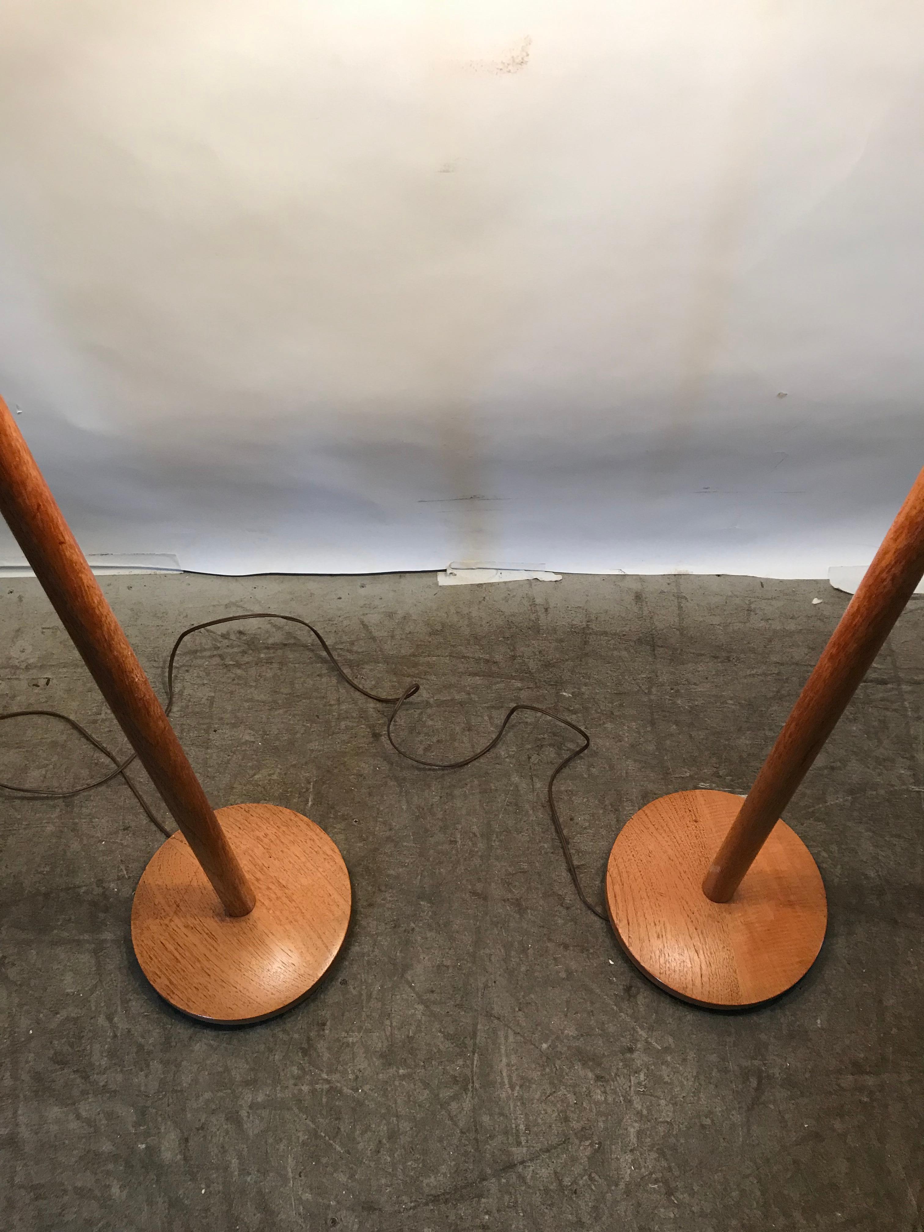 Matching pair of teak floor lamps attributed to Uno and Osten Kristiansson, Sweden, 1950. Nice original condition, retains original lamp shades.