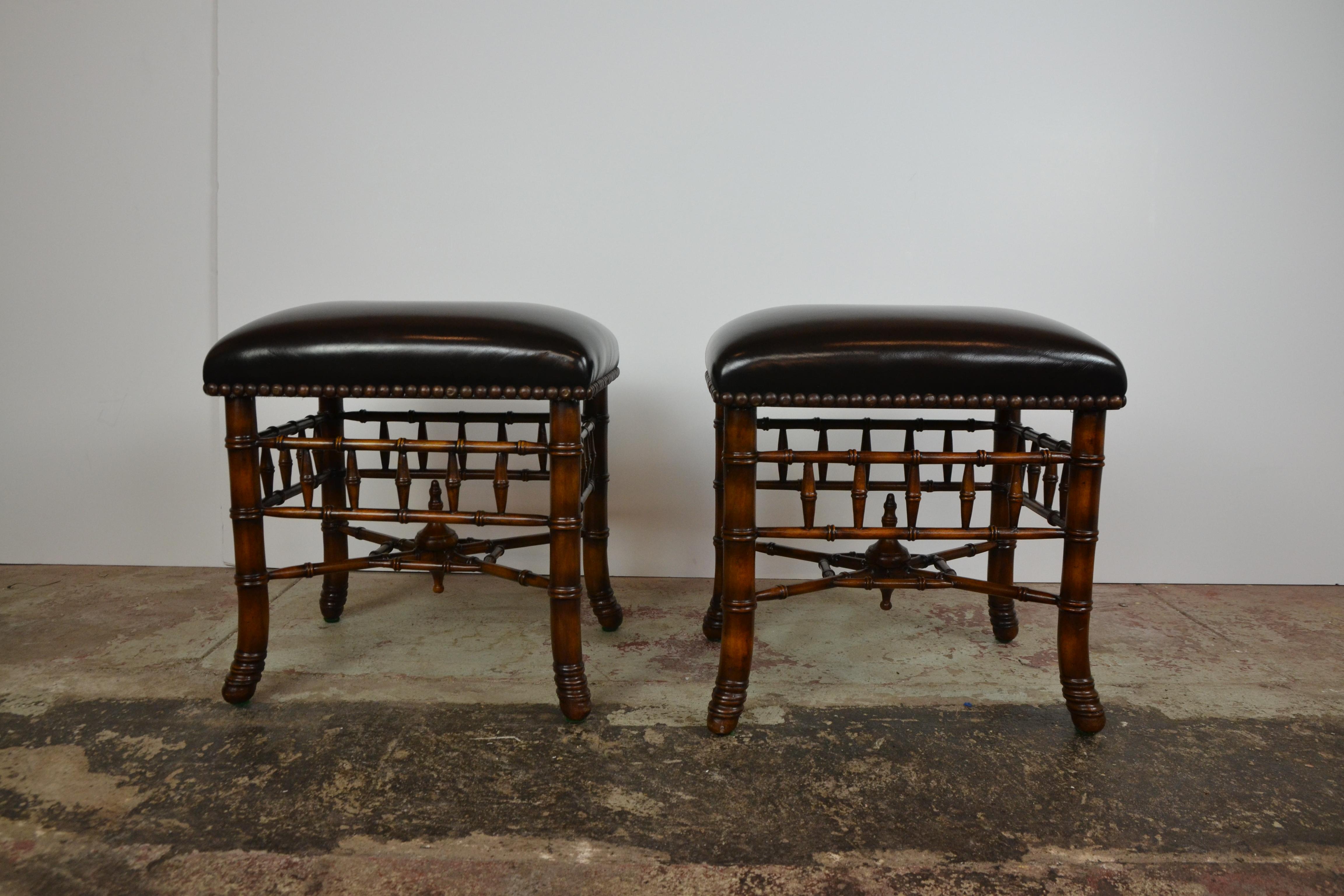 A wonderful pair of benches or stools of exceptional quality. Finely carved legs, rails and stretchers that show their quality detail from any angle. Faux black leather tops with heavy brass studs. Theodore Alexander.