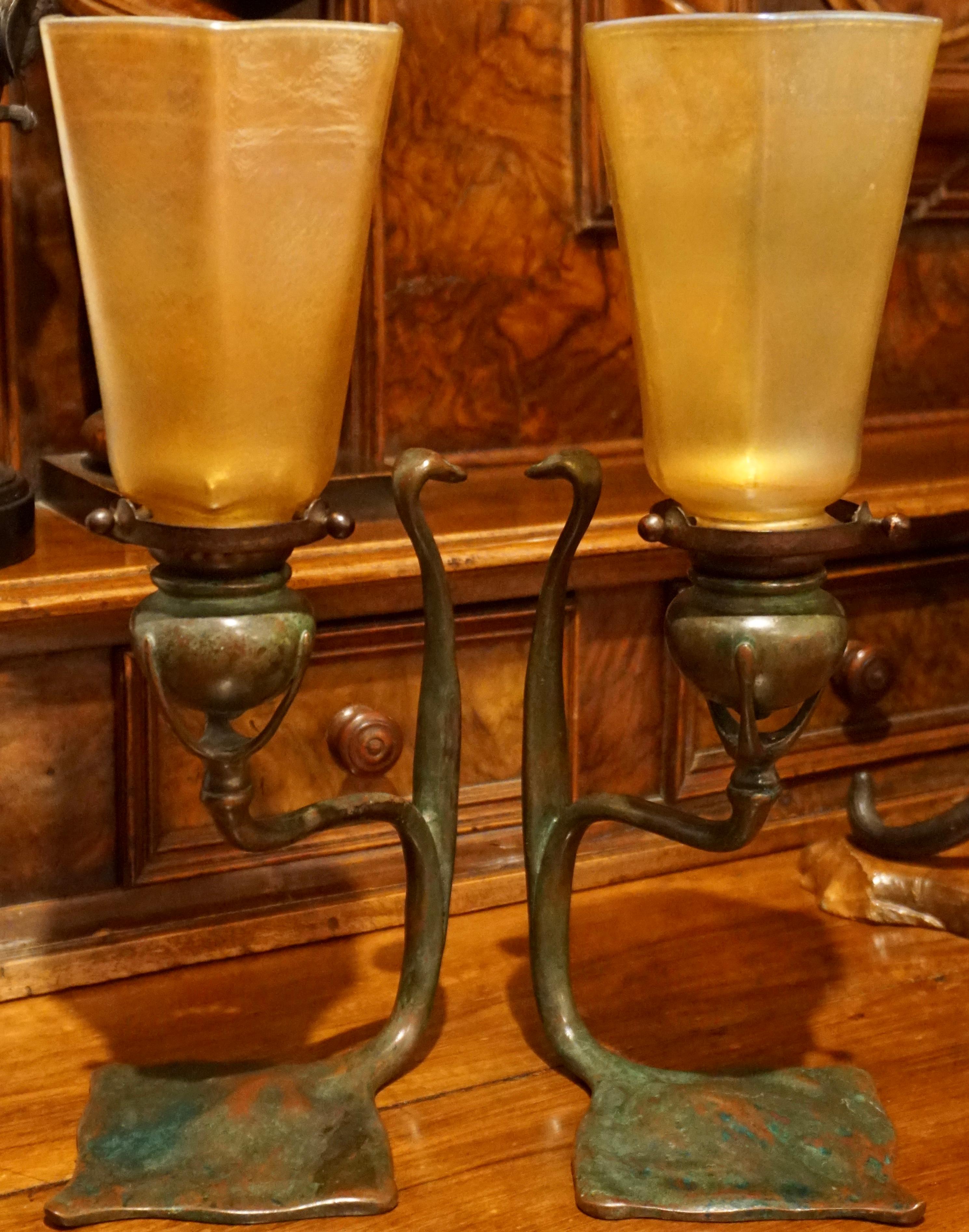 A rare pair Tiffany Studios cobra bronze candlesticks with L.C.T. Favrile lamp shades. Absolutely beautiful green, red and brown patina with no issues; just age. The gold Favrile signed L.C.T. Glass shades could not be matched more perfectly.