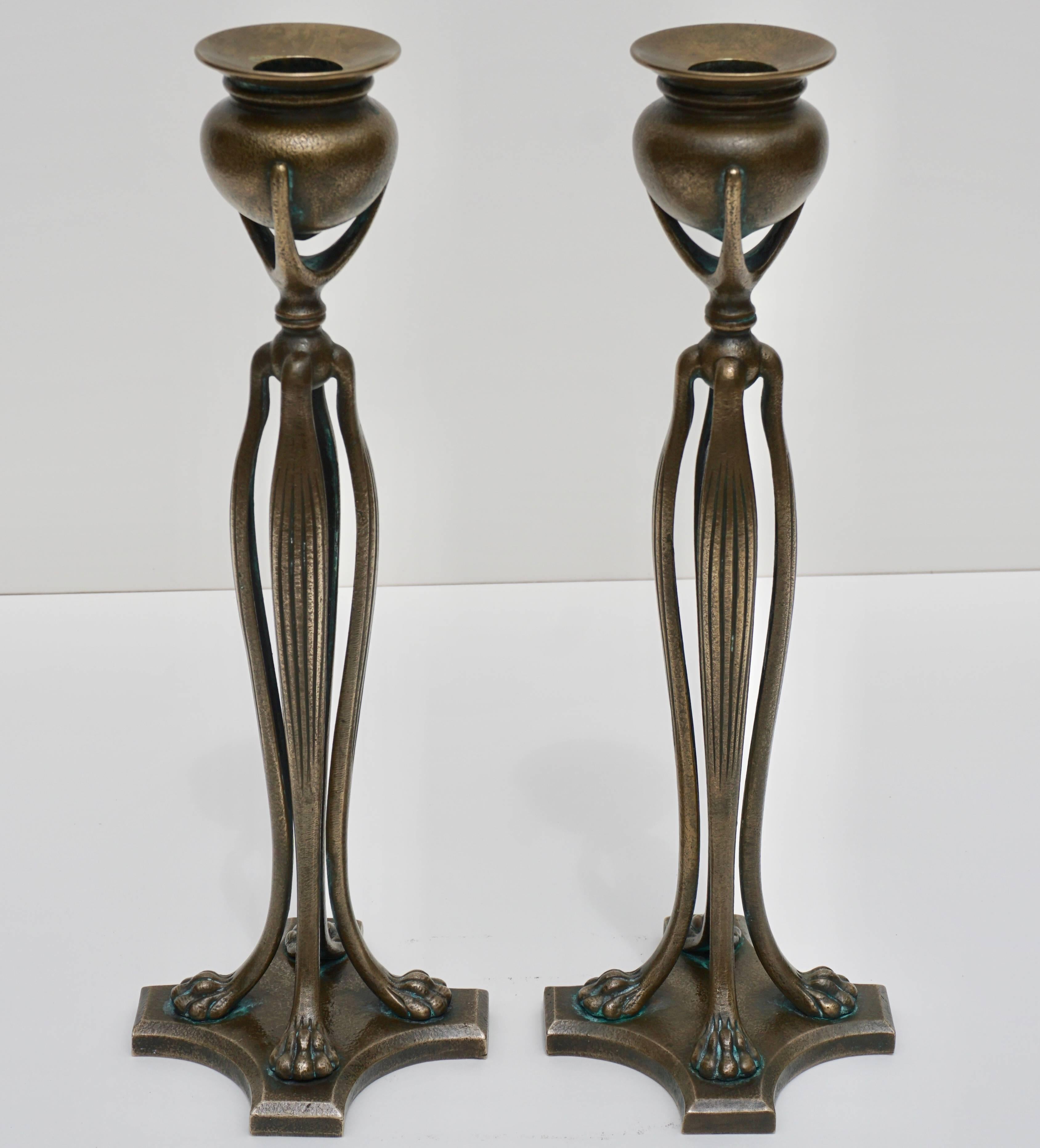 Tiffany studios New York Art Nouveau candlesticks, 1900. These bronze patinated and gilt candle holders are in mint condition. Supported by four lion’s paw feet on a cross stand. Light brown to gold textured finish patina.

Stamped: TIFFANY STUDIOS