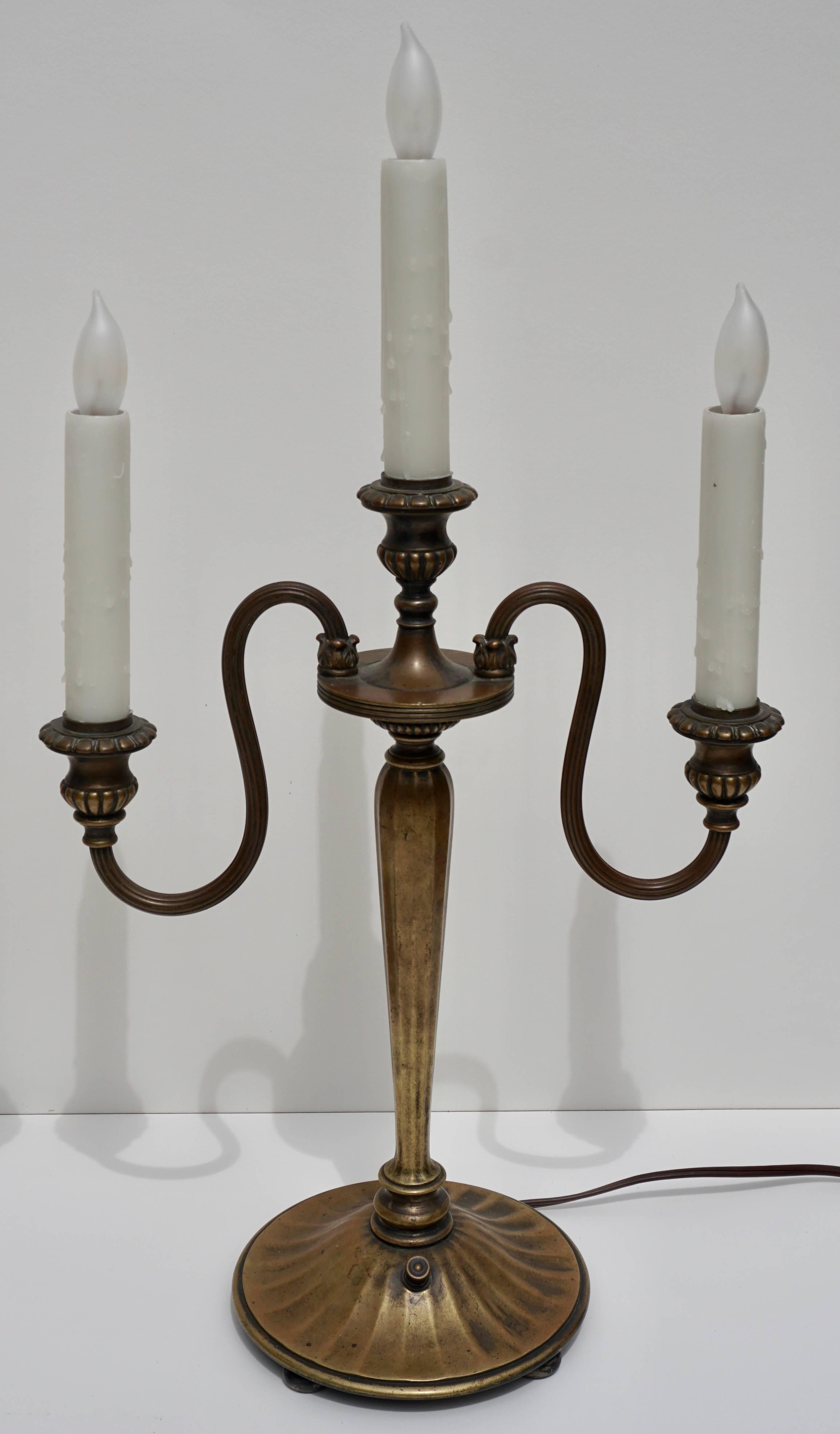 A very rare pair of Tiffany Studios candlestick lamps that are fully functional and produce a warm yellow and orange glowing light. Each candelabra lamp has two curving ‘S’ arms and a centre comprising three bobech lights (currently with 10W soft