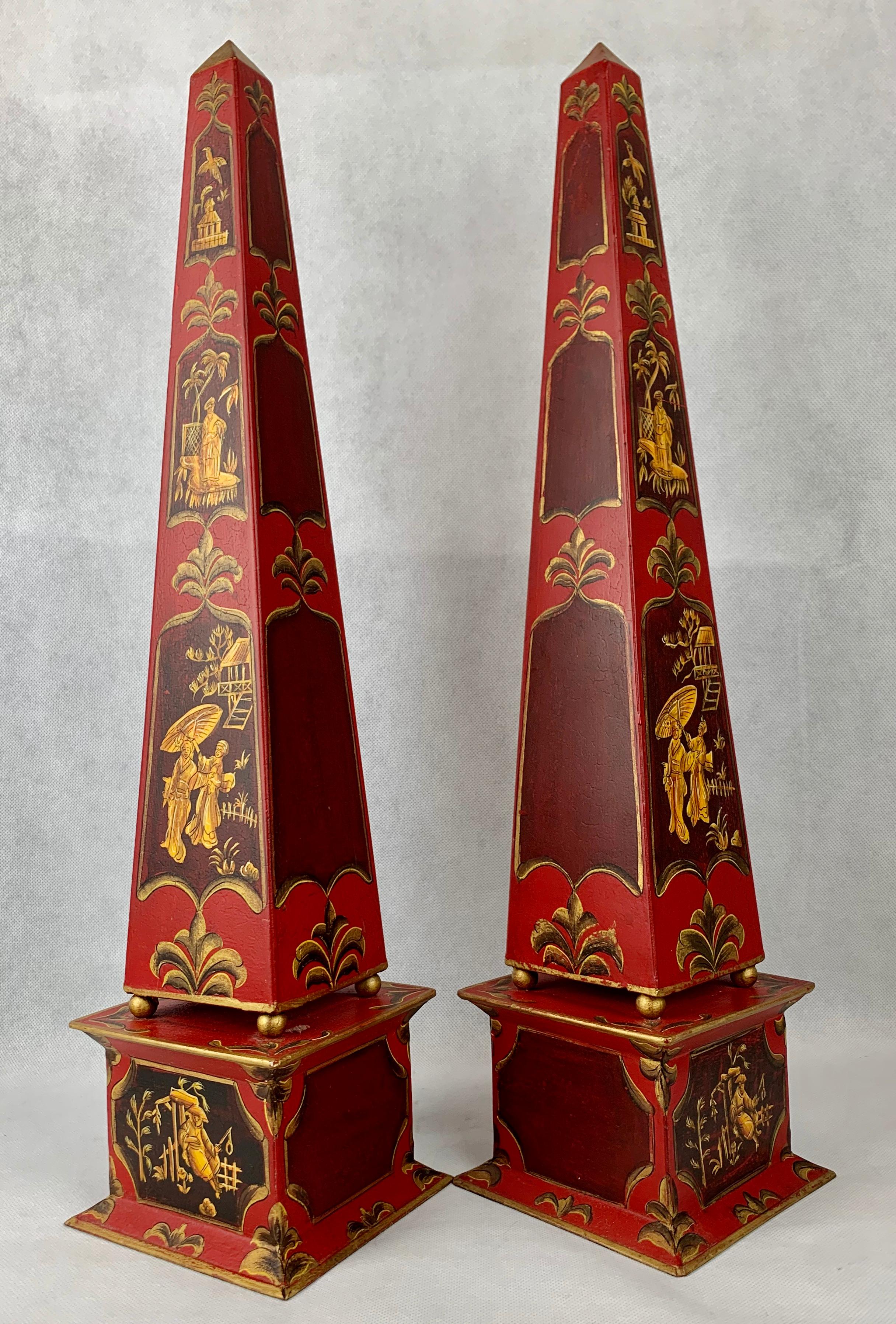 Pair of hand painted tôle obelisks with a chinoiserie motif. Two sides are paneled with figures and scenes. The other two sides have solid painted panels. There are no dents or cracks.

Measures: Height 22.25