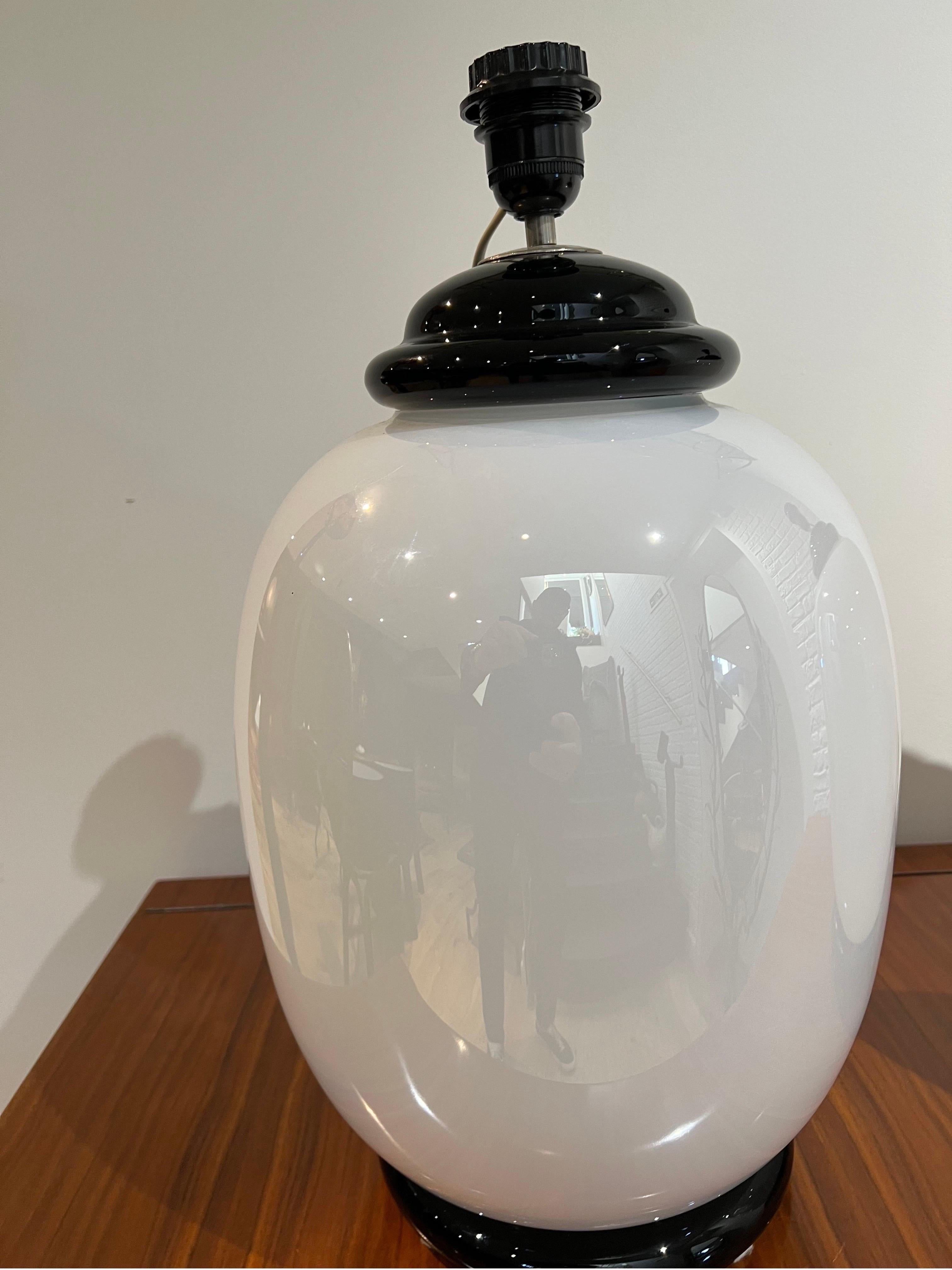 A gorgeous pair of hand blown white opaline & black murano glass table lamps depicting large scale lidded vases . Designed & labelled by Tommaso Barbi Roma Italy . Measurements are without the black optional shades .