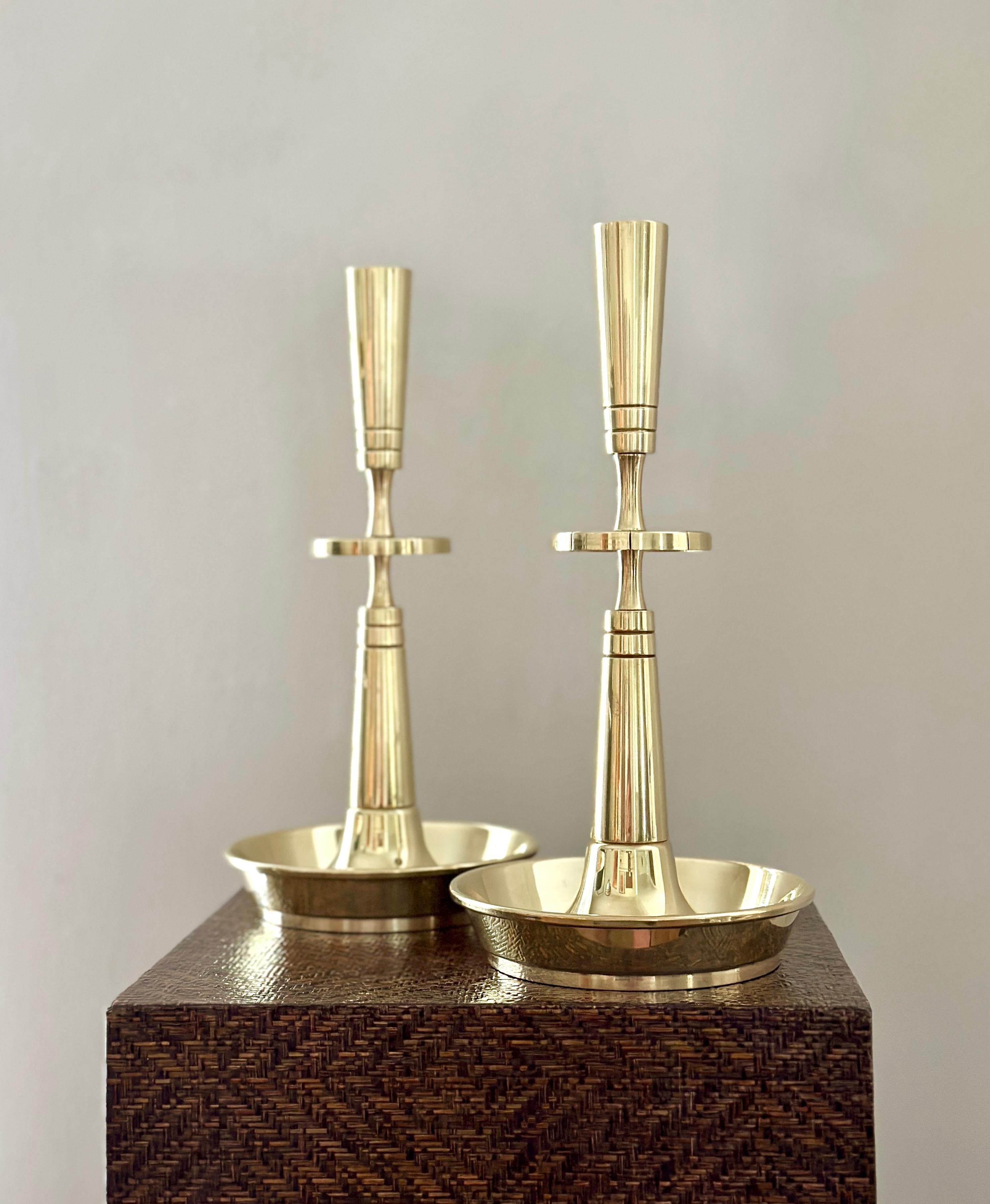 DESCRIPTION

A pair of solid brass candlesticks designed by Tommi Parzinger for Dorlyn Silversmiths. The candlesticks stand approximately 10 5/8 inches tall and the base is 5 1/2 inches at the top of the lip of the base. One candlesticks is embossed