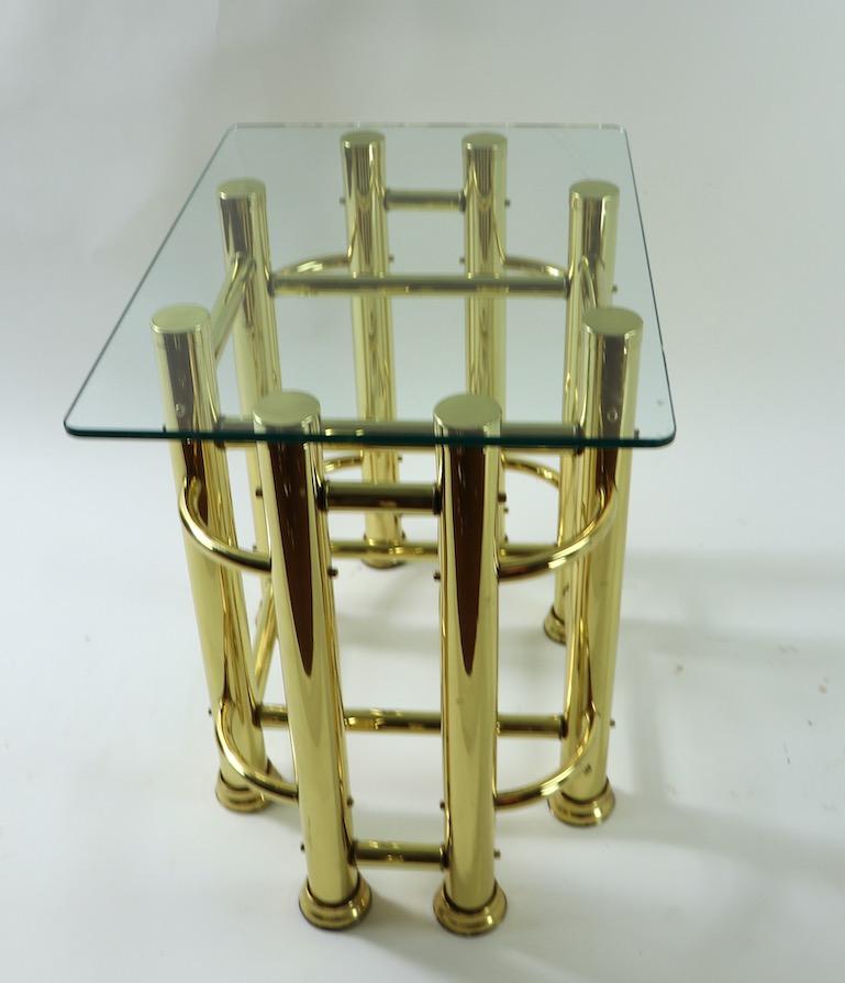 Pair of Mod Style tubular brass based tables with thick (.50 inch) plate glass tops. Architectural constructivist design bases in shiny brass finish, chic, stylish, clean and ready to use. Both tables are in very good original condition, showing