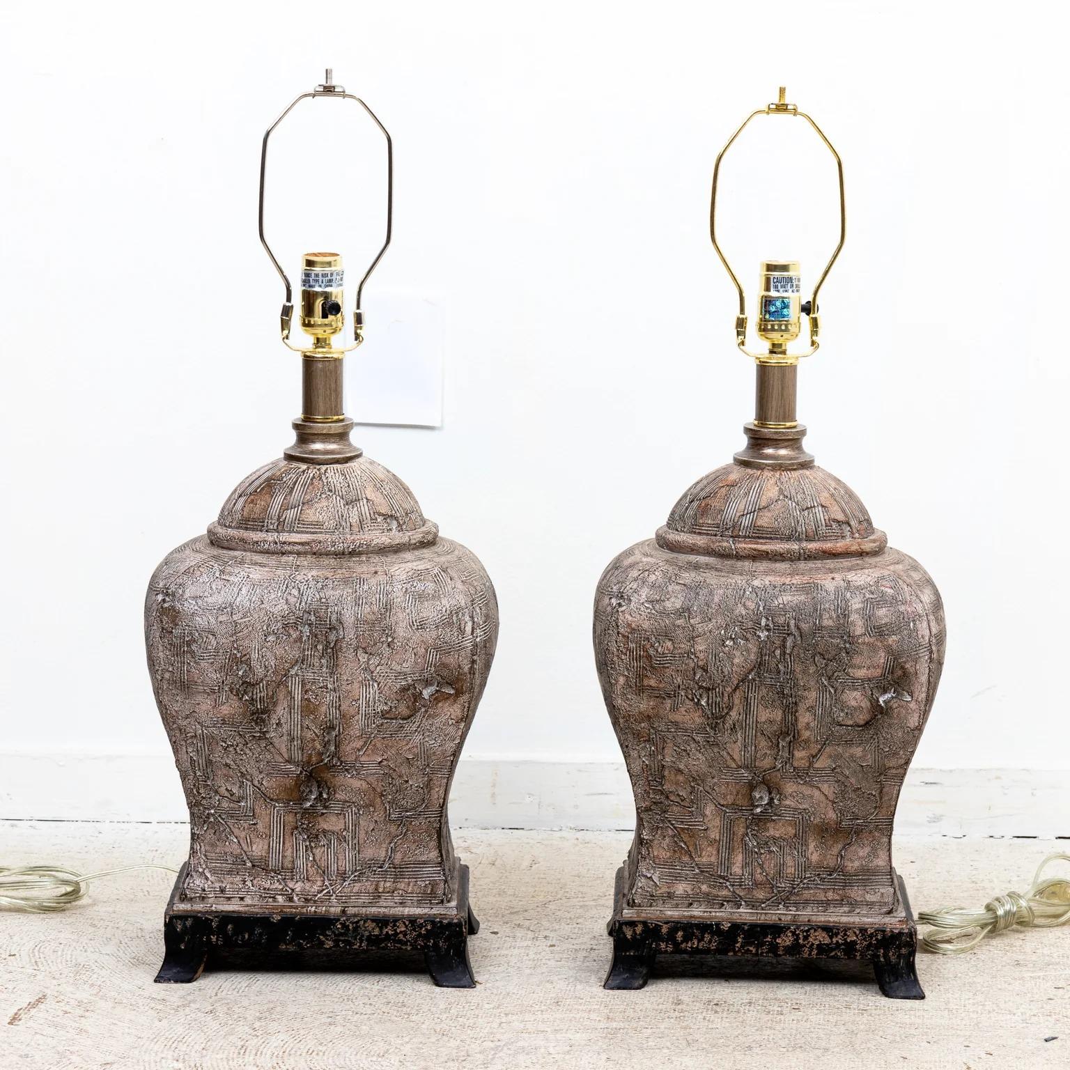 Pair of composition urn form lamps with distressed terracotta appearance, raised on black painted bases. Please note of wear consistent with age.