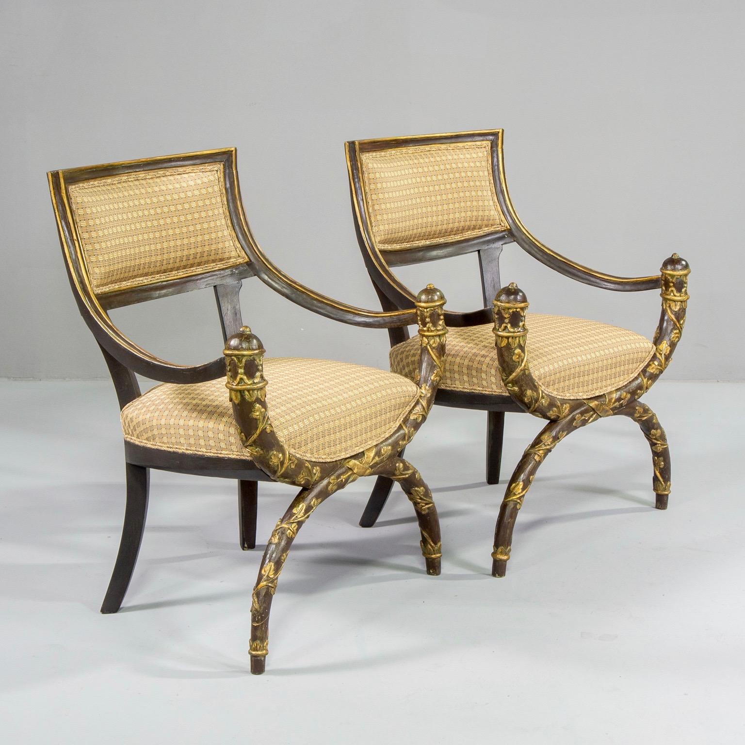 Pair of circa 1880s Savonarola style armchairs have painted and gilded frames with hand carved vine and leaf design on the face of the base. Newly upholstered in Robert Allen fabric with a woven grid pattern in gold hues. Sold and priced as a pair.