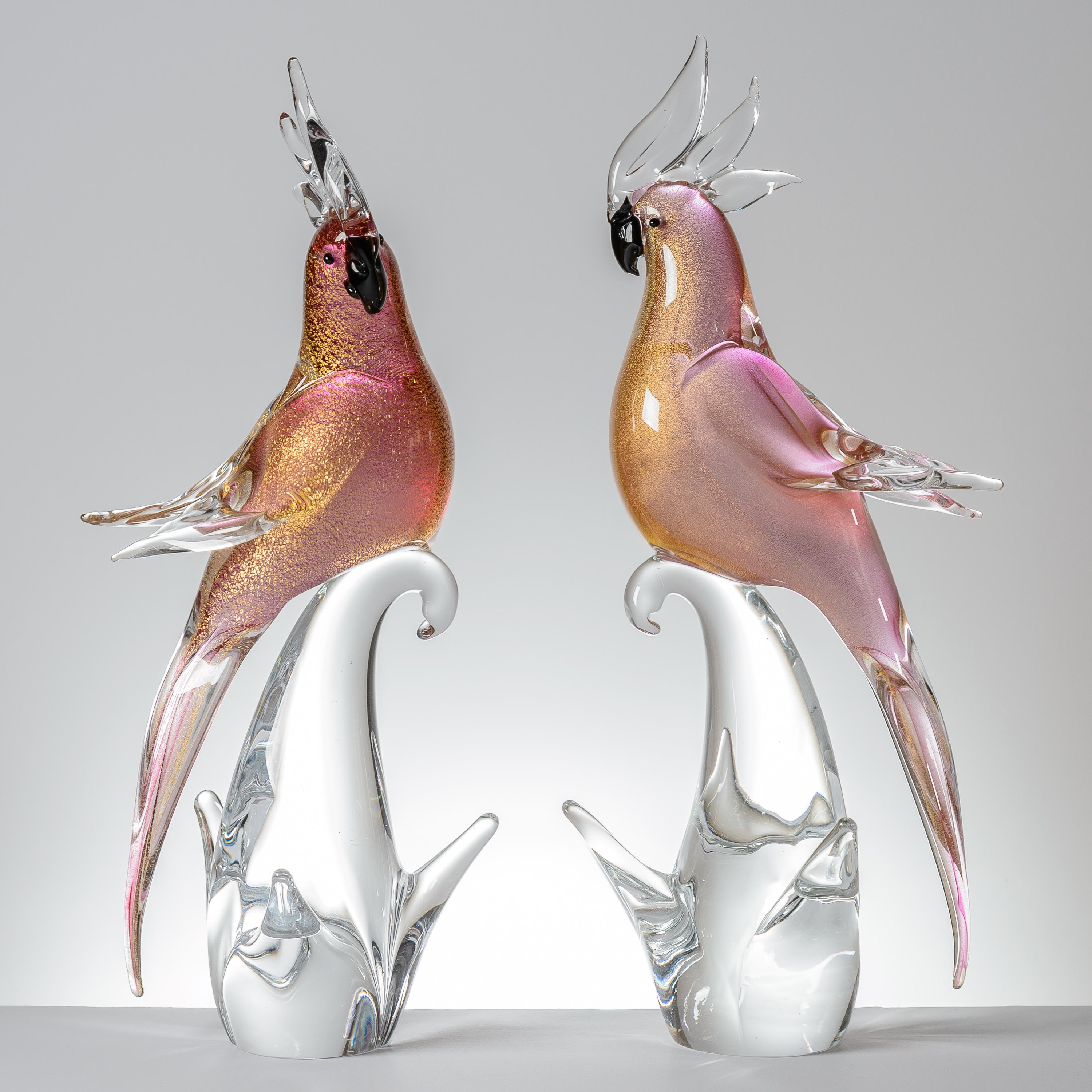 A pair of tall vibrant pink and clear blown art glass bird sculptures by one of the re known firms from the Isle of Murano in Italy. This pair features nice details to their faces and bodies with just the right amount of pink and blown 24 karat gold