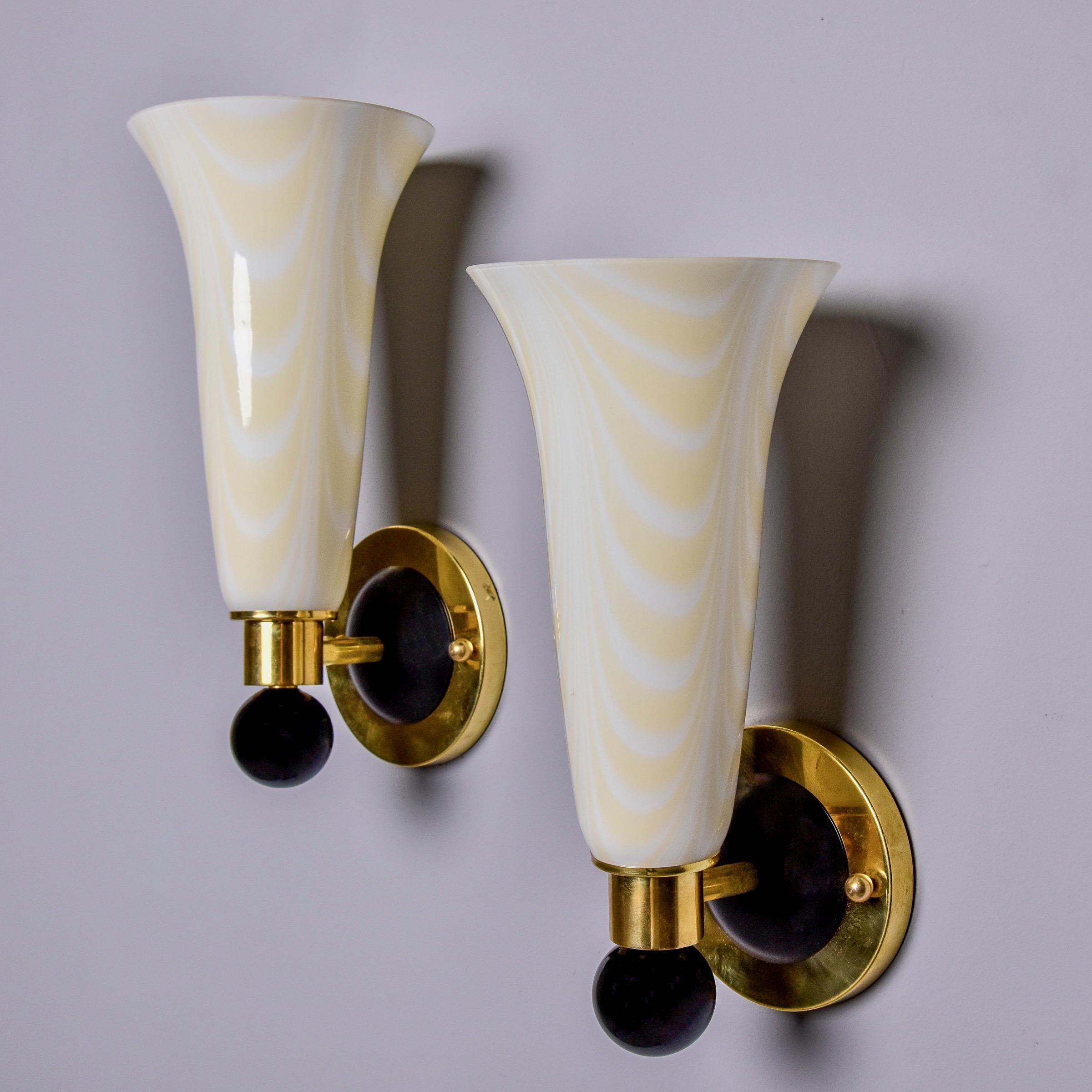 Questa coppia di appliques in vetro di Murano di Venini è stata trovata in Italia e risale agli anni Novanta. Ogni applique ha un paralume alto in vetro in una tonalità molto chiara di giallo e bianco, montato in ottone lucido con un terminale in