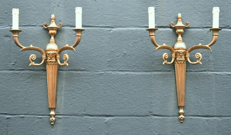 Pair two arm bronze wall sconces by Versace. Center figural Medusa face. Fluted body with urn shaped top. Dimensions: 13.5