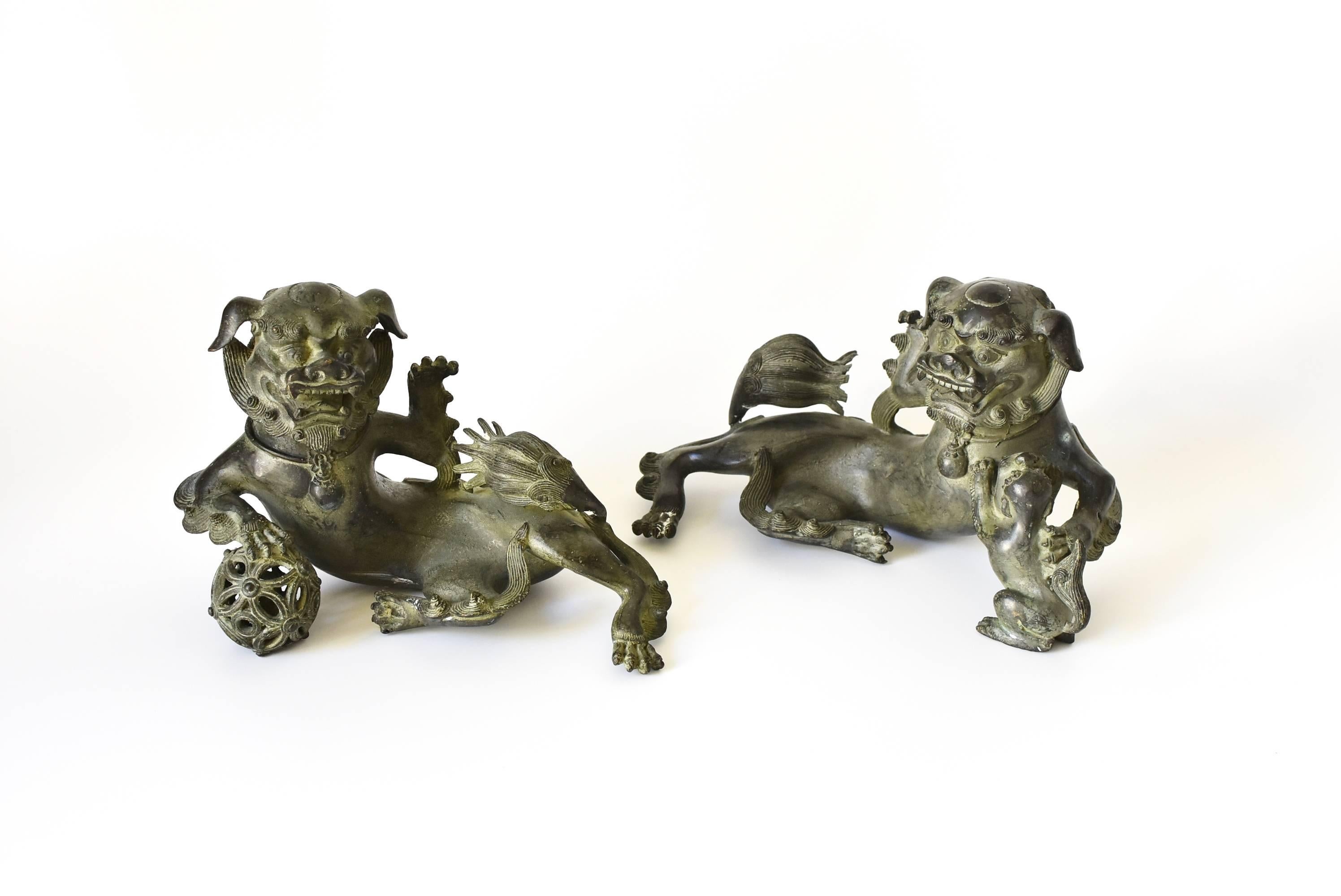 A pair of absolutely stunning, extremely fine bronze foo dogs. These pieces are very refined with every parts of the foo dogs well defined. The male holds a globe firmly in his paw, symbolizing the universe. The ball is hollowed. The female holds a
