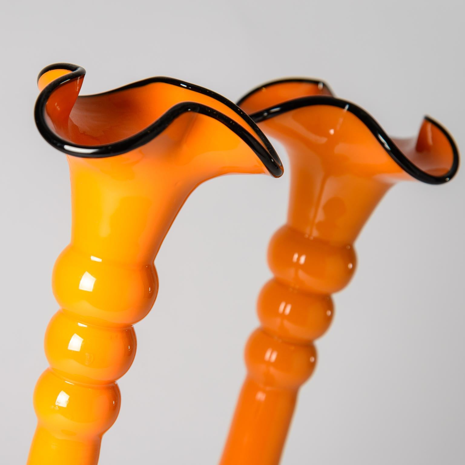 An unique pair of vintage blown glass vases with a fun orange color and accented with black glass to their tops. Signed on the bottom and in very good  condition