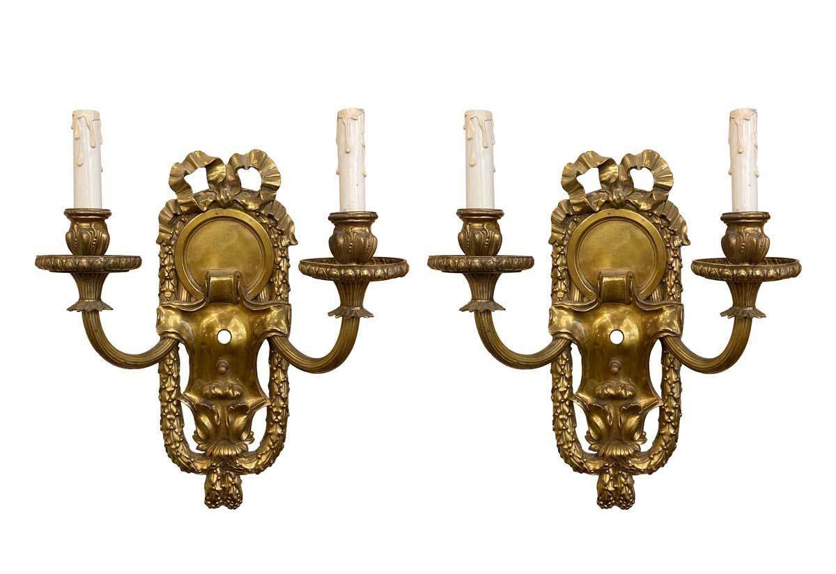 Crafted with meticulous detail, these ornate, heavy bronze sconces feature a captivating ribbon motif, showcasing the craftsmanship synonymous with E.F. Caldwell. With a design that exudes Victorian opulence, these two-arm wall sconces not only