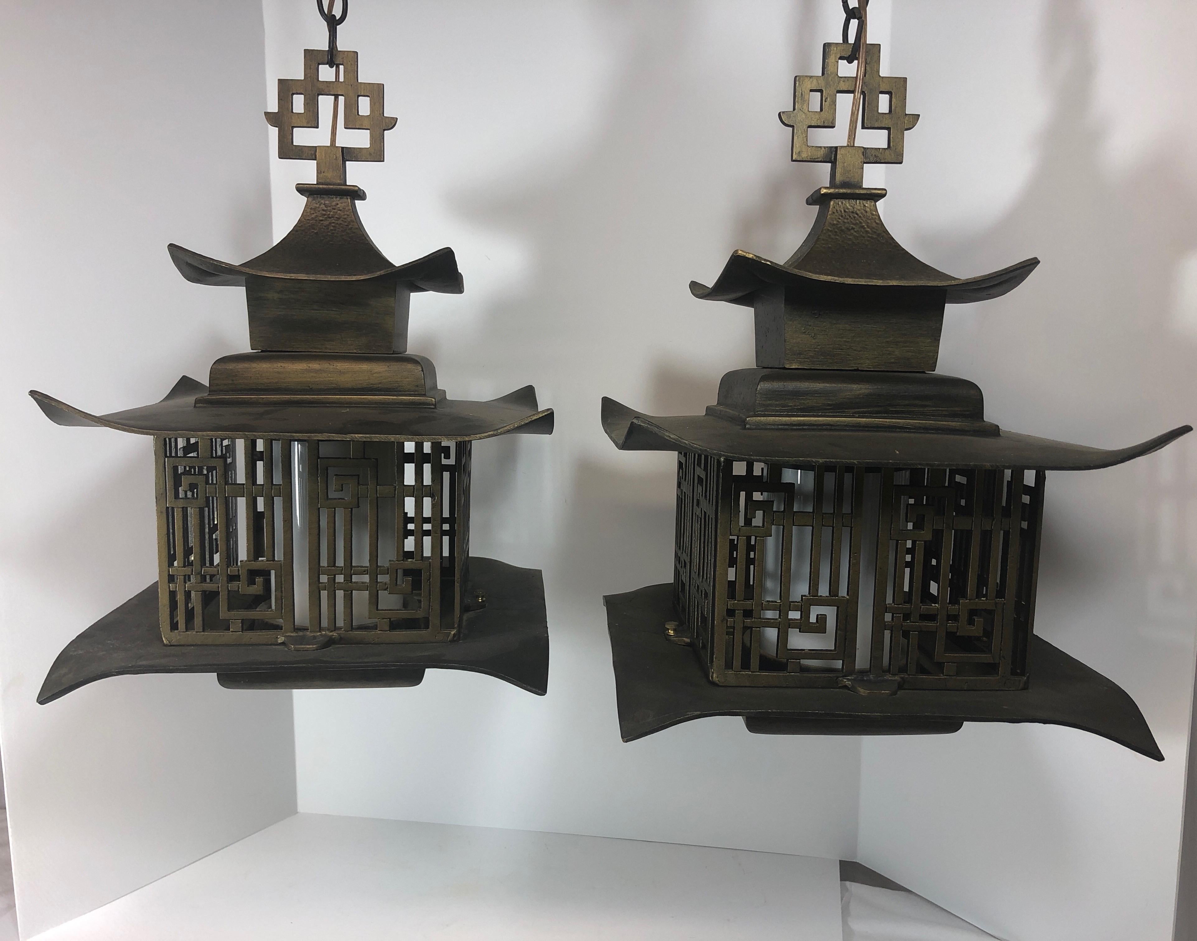 Pair of vintage Chinese pagoda lanterns or chandeliers. Made of cast iron with patinated antique brass finish. Single bulb inside white glass shade. Both in working order. 60