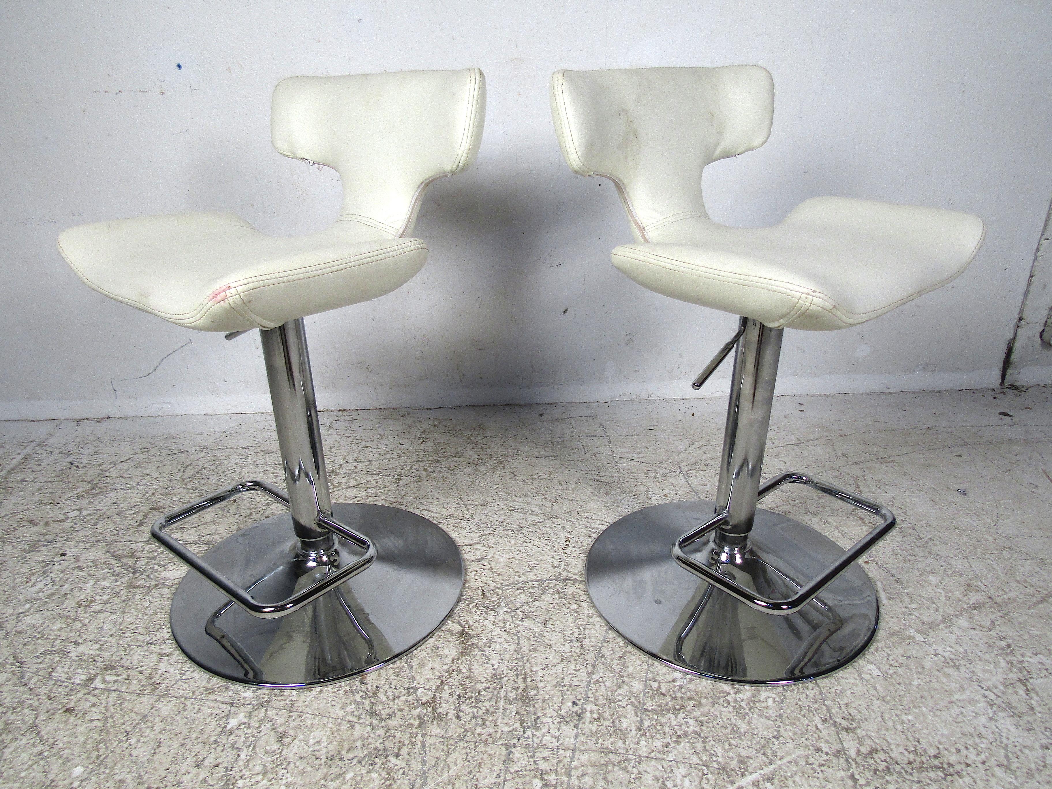 Nice pair of vintage stools. Adjustable height settings. White vinyl upholstery. Unusual design on seat and backrest. Sturdy chrome bases and footrests. Please confirm the item's location with the dealer (NJ or NY).