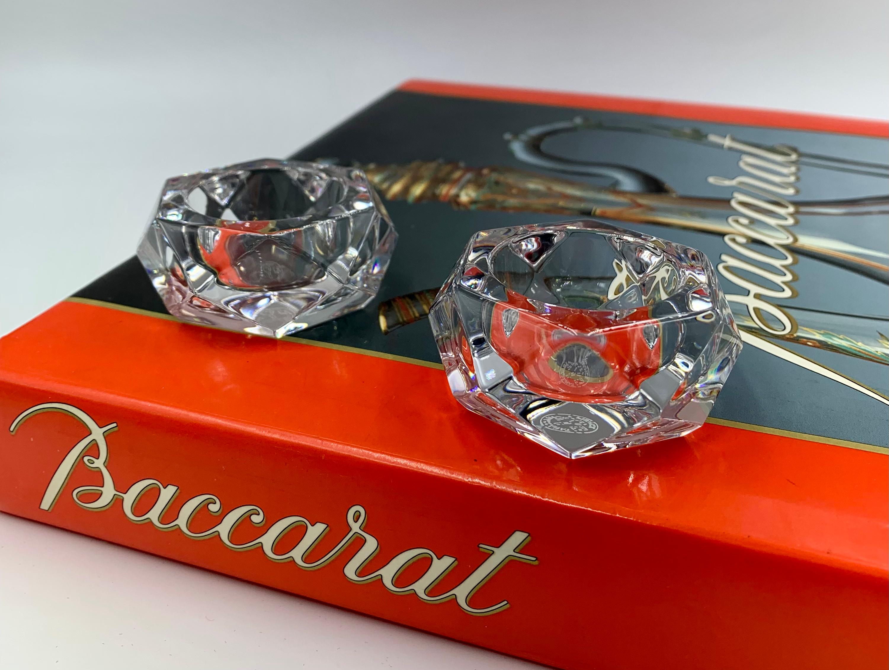 Feines Paar Baccarat Kristallsalzkeller in ausgezeichnetem Zustand mit Originalverpackung. Die Seiten sind rauten- und dreieckförmig facettiert, die Oberseite hat eine runde Aussparung für das Salz. Signiert auf den Sockeln mit der runden
