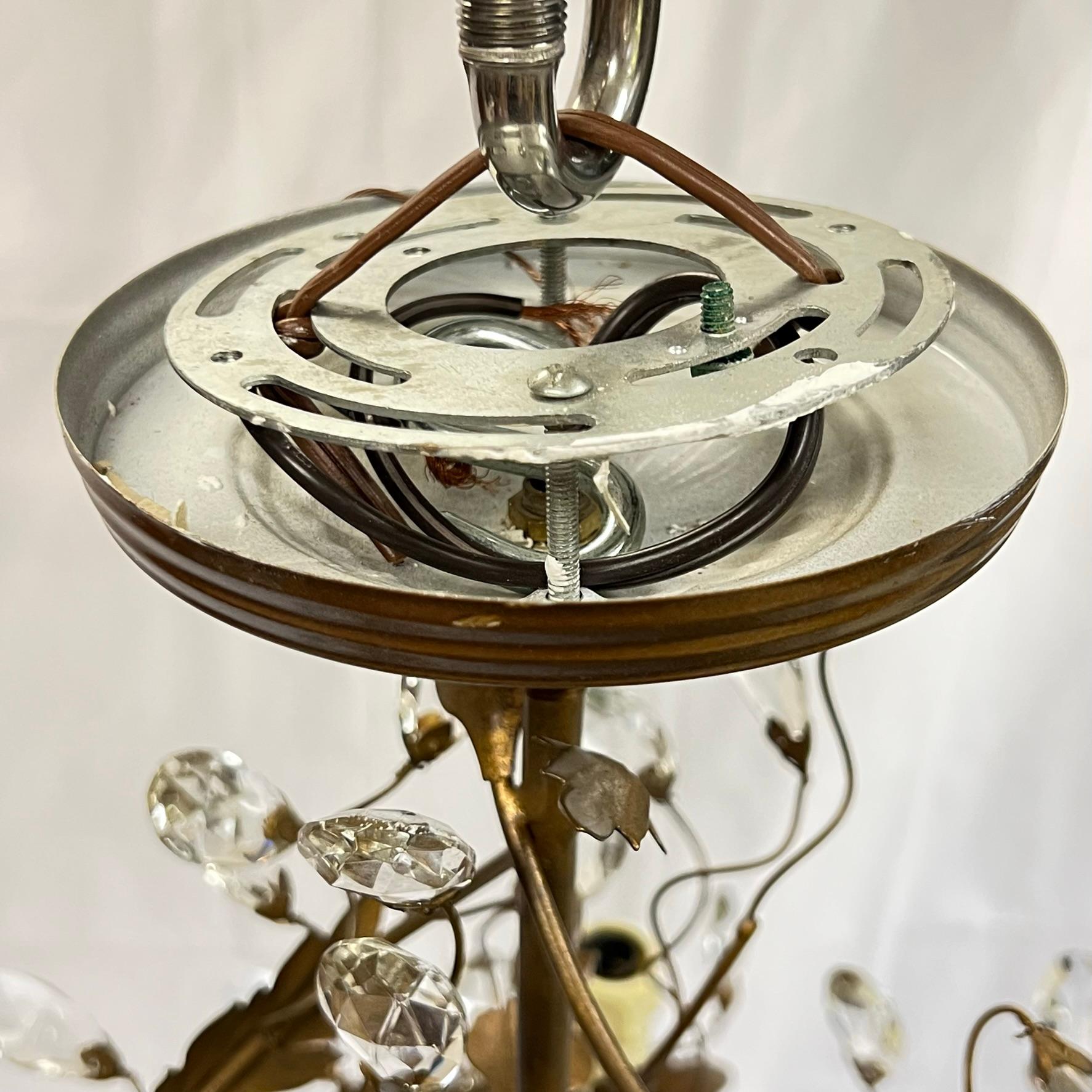 Pair of vintage patinated metal chandeliers in the Louis XV fashion with foliate design and faceted cut glass leaves and three sockets with faux candle covers. Ready for use.