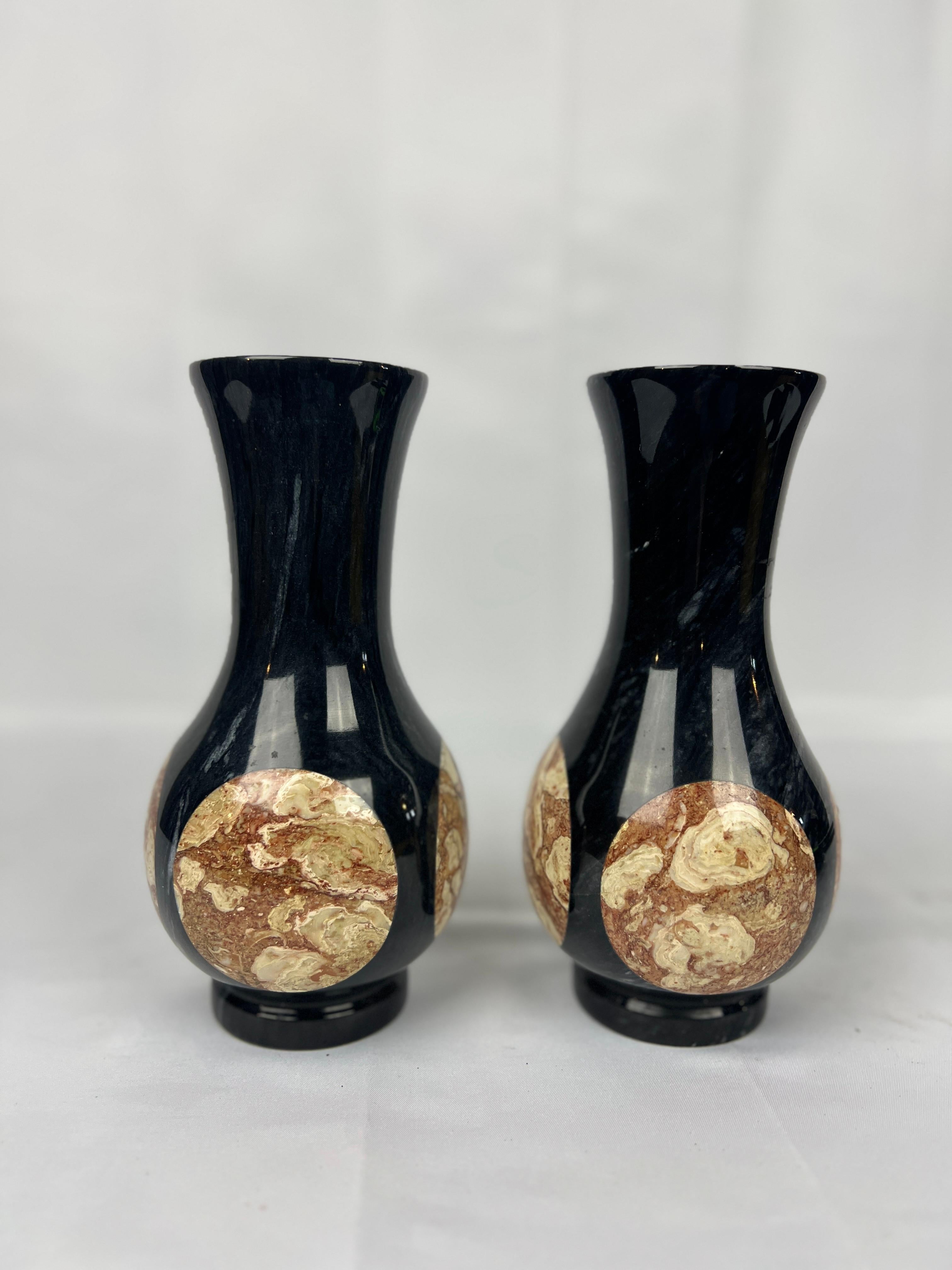 Questa elegante coppia di vasi vintage presenta un design sofisticato realizzato in onice nero con inserti in marmo a contrasto. I vasi sono splendidamente proporzionati, con silhouette pulite e affusolate che riflettono l'estetica moderna della