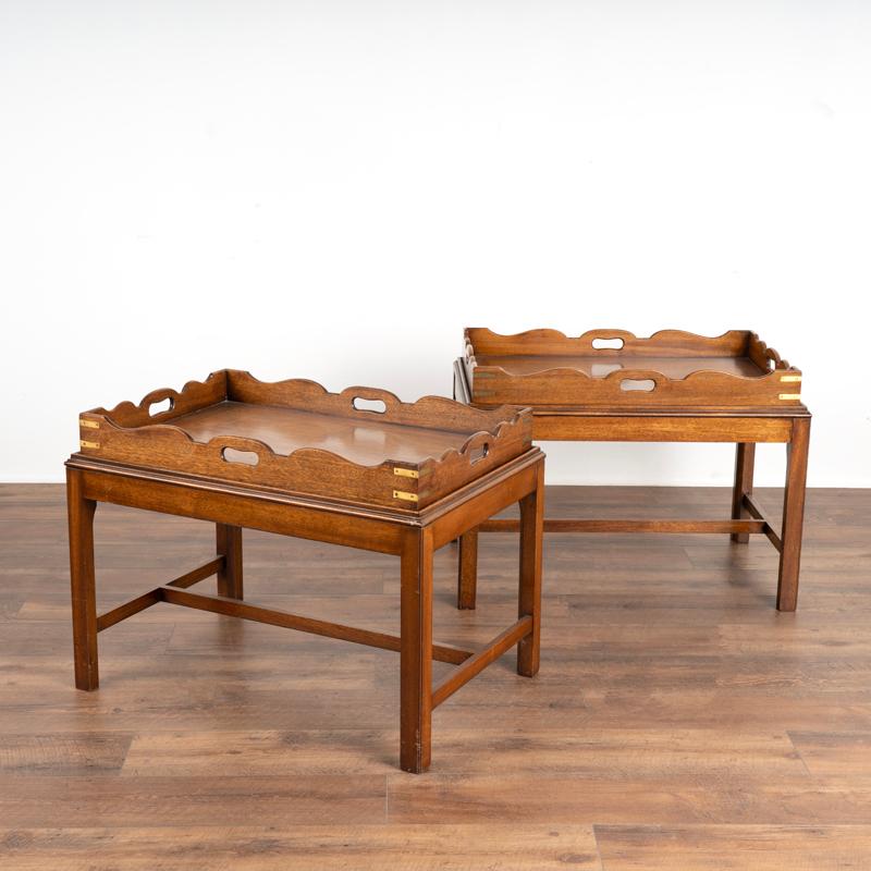 This classic pair of mahogany English butler's tables features removeable trays with scalloped sides, sold brass hinges and open handles for serving. The two side tables have a slight trim that helps hold the tray in place. Any scratches/knicks are